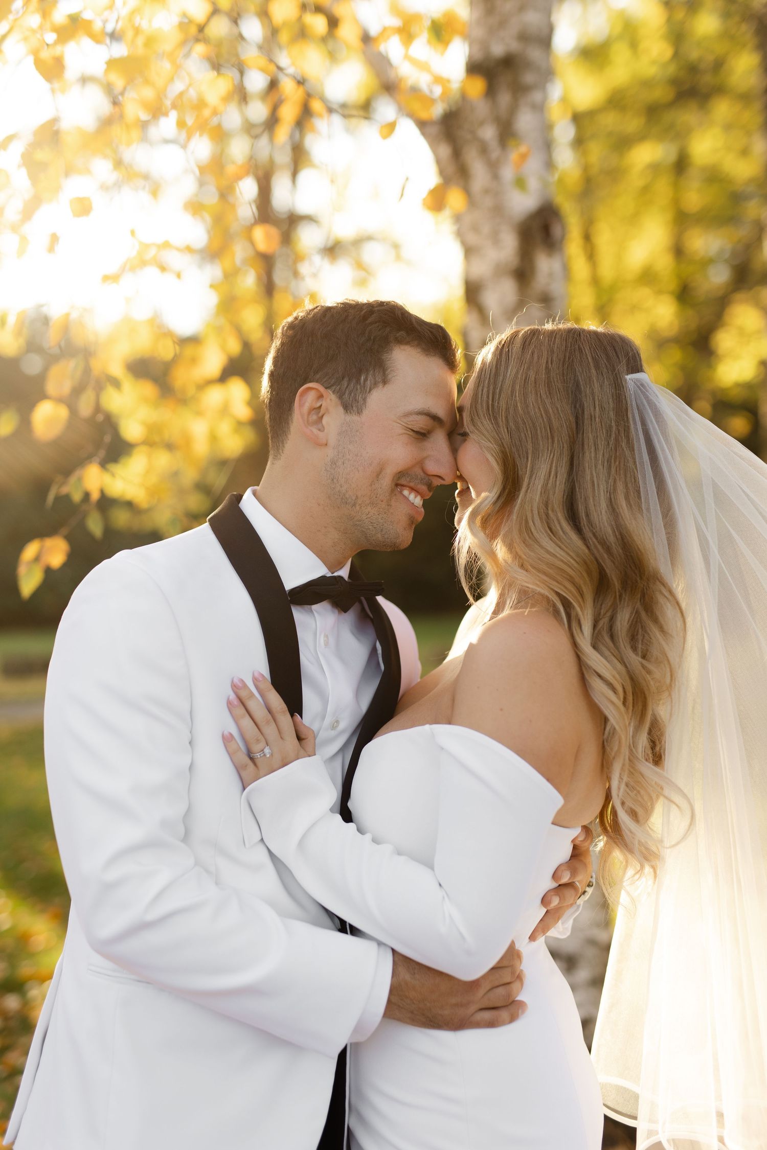Tender wedding portraits captured in warm autumn light with white formal attire.