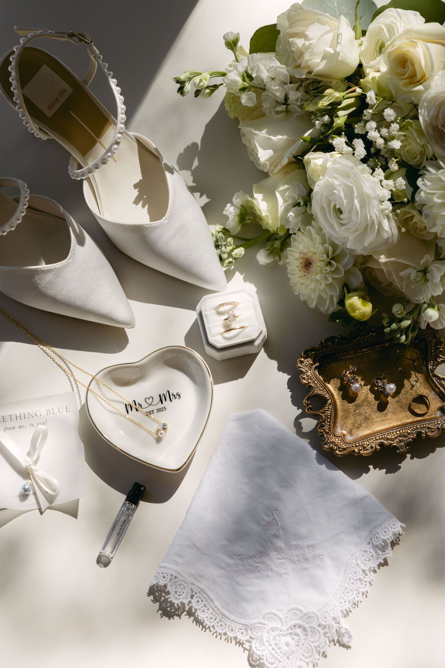 Wedding details including white flowers, bridal shoes, and delicate lace handkerchiefs in natural light.