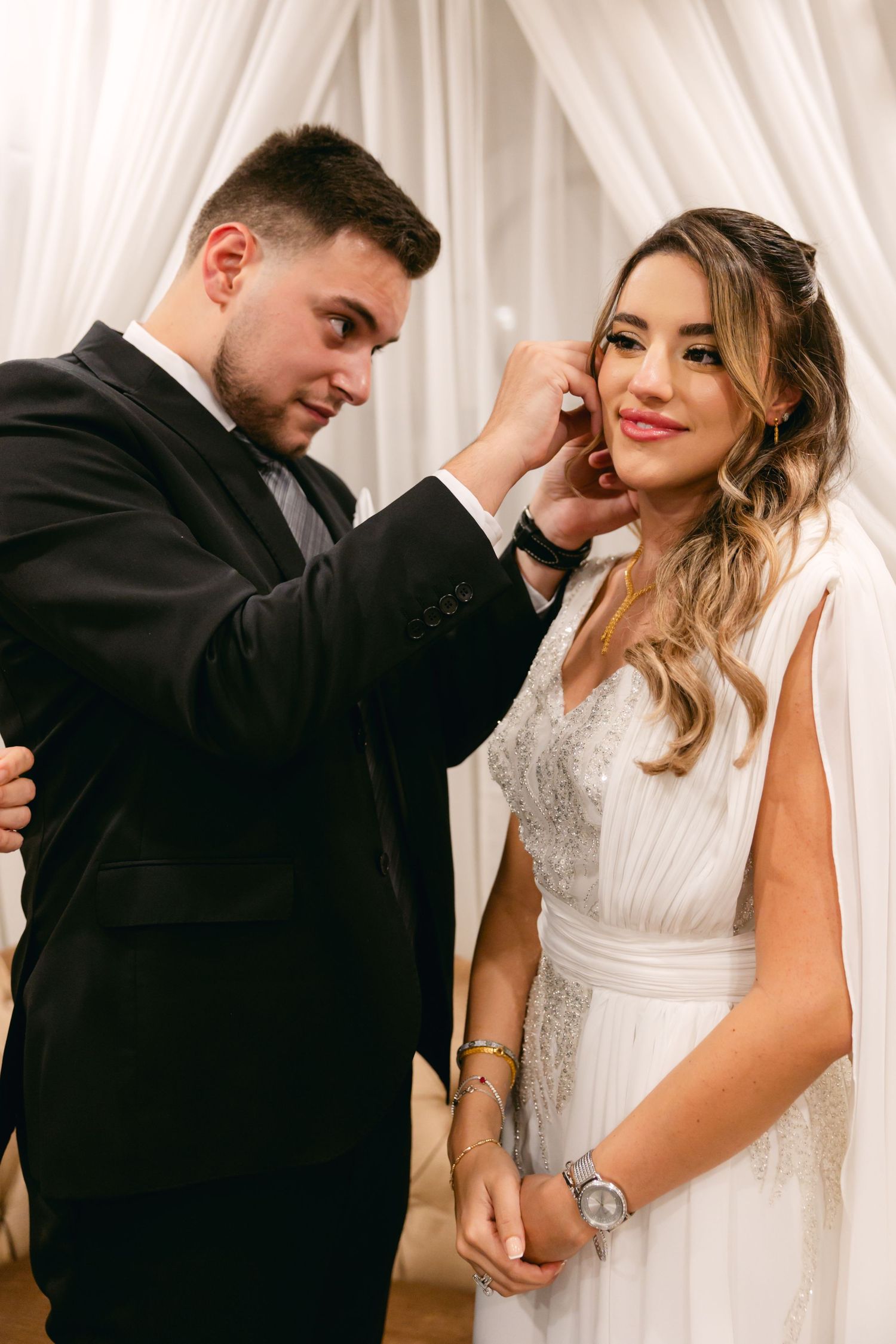 Romantic wedding moment captured against white draped backdrop.