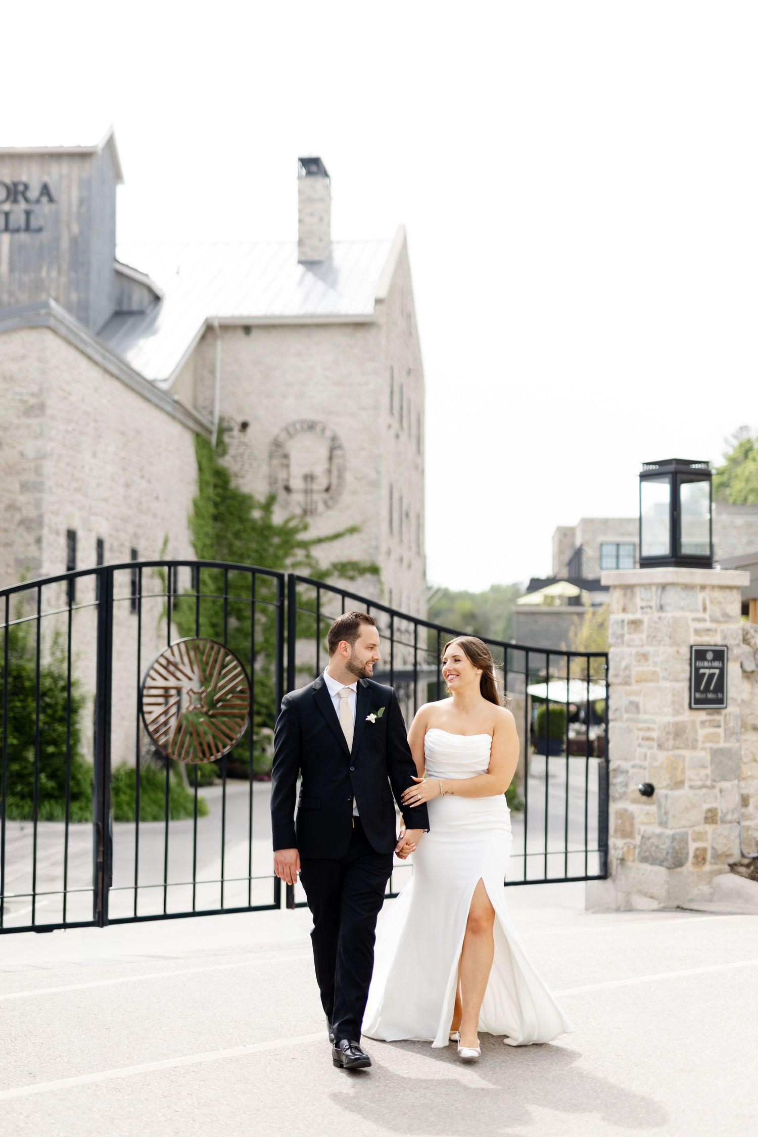 Bride and groom walking hand in hand outside a stone building venue on their wedding day.