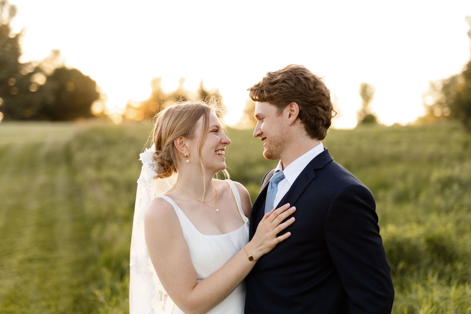 Intimate wedding portrait captured during golden hour in a natural outdoor setting.