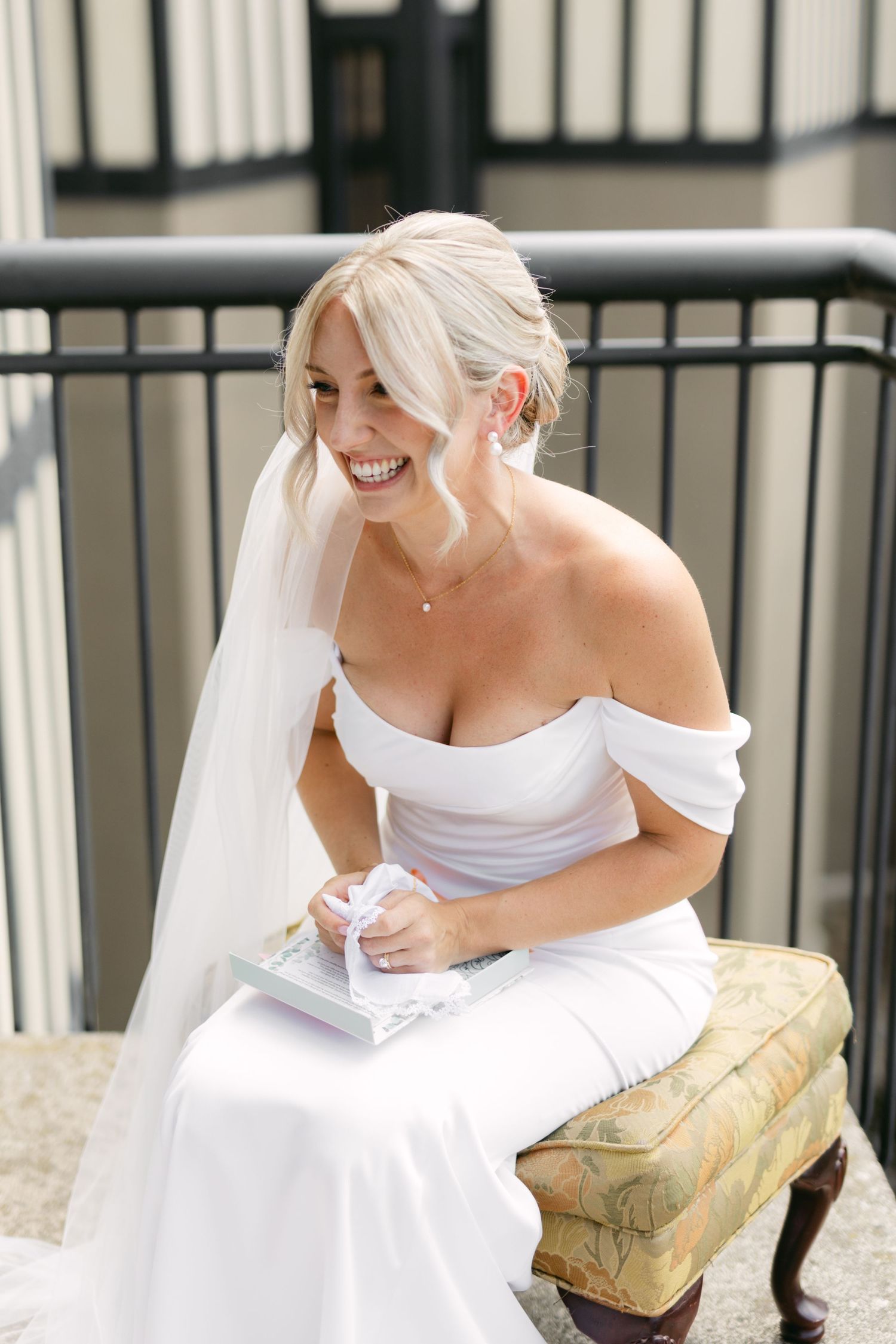 Happy bride in white dress reading personal letters on an outdoor porch.