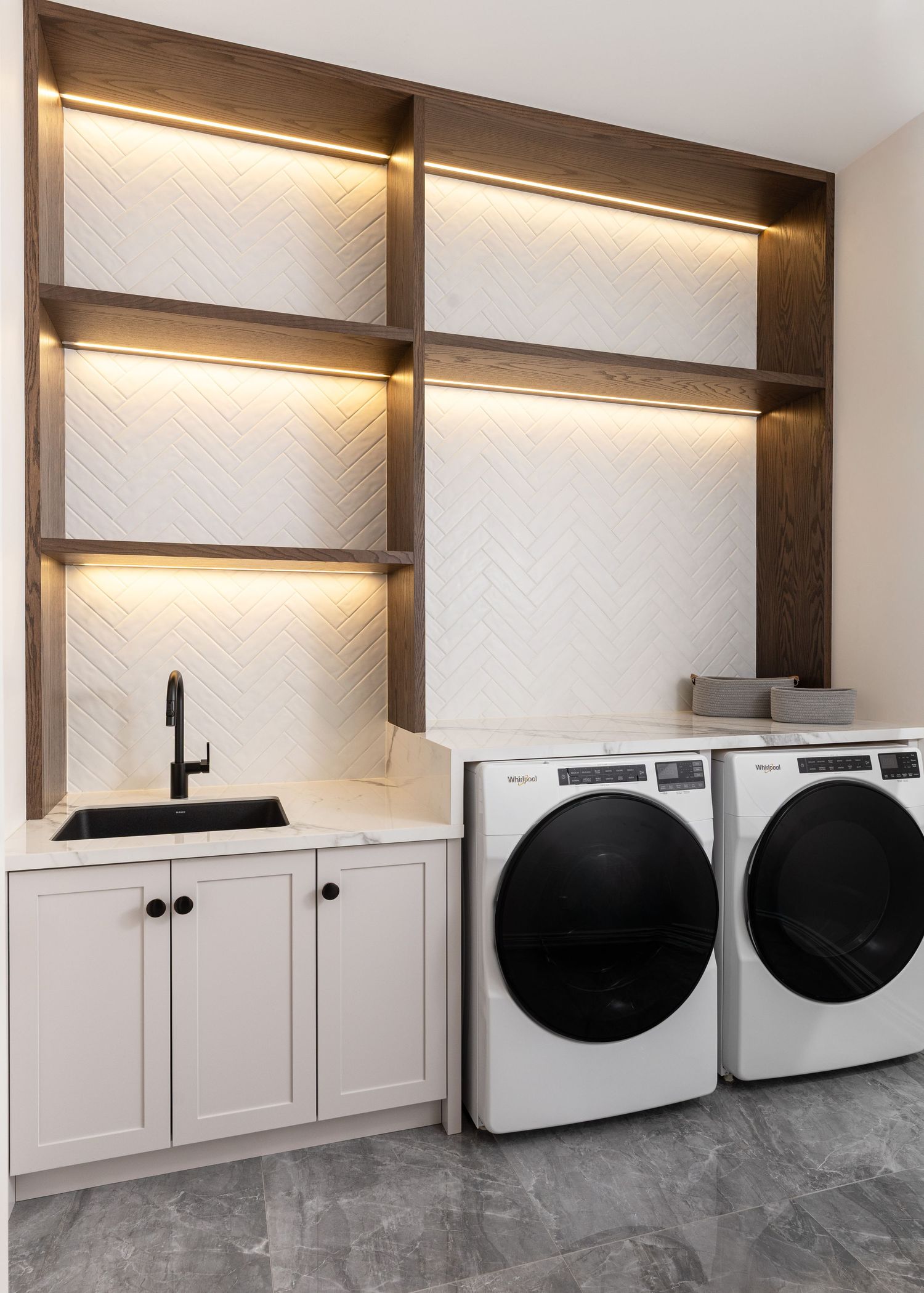 Modern laundry room with white cabinets and black appliances.