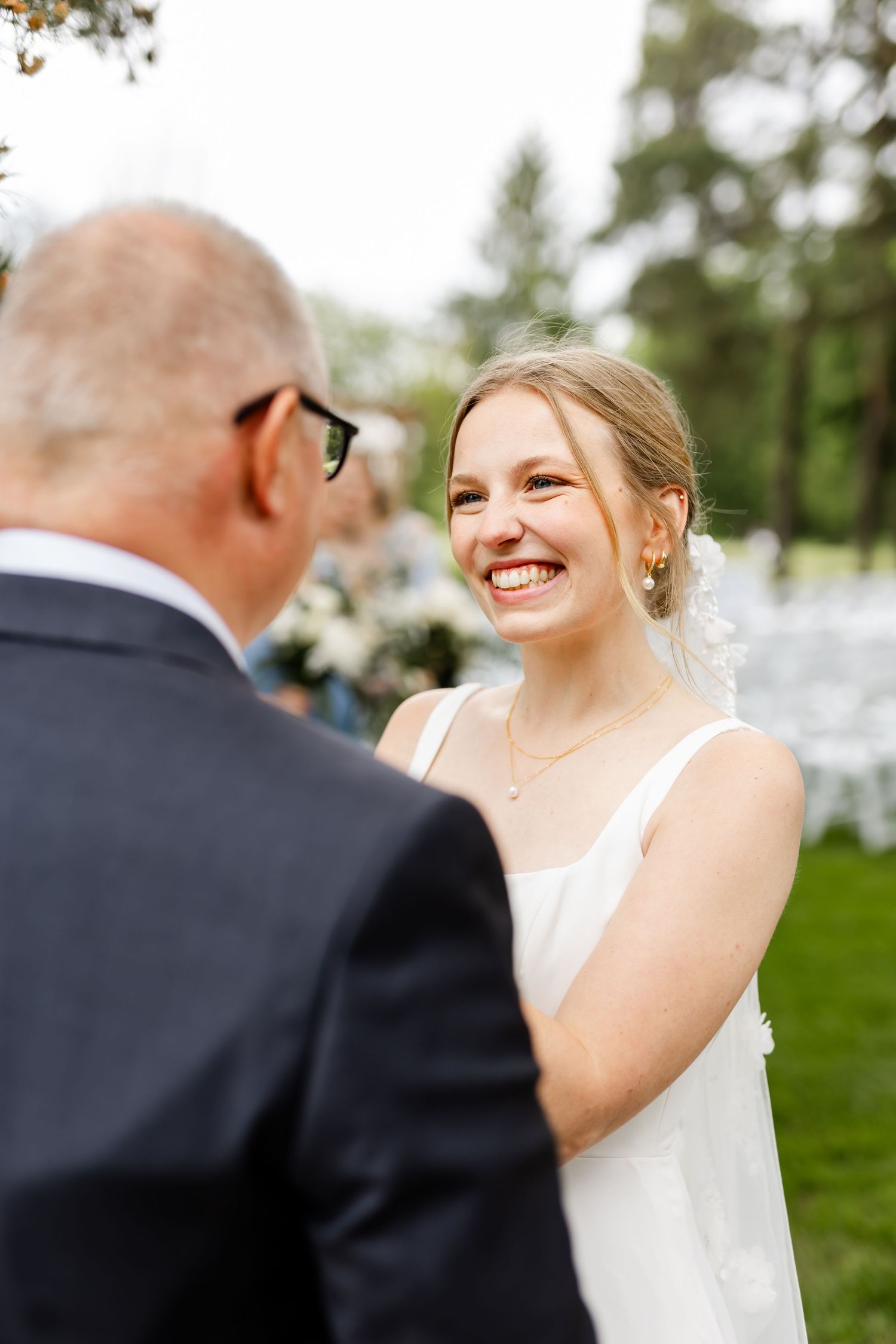 Joyful outdoor wedding moment captured between bride and wedding party member.
