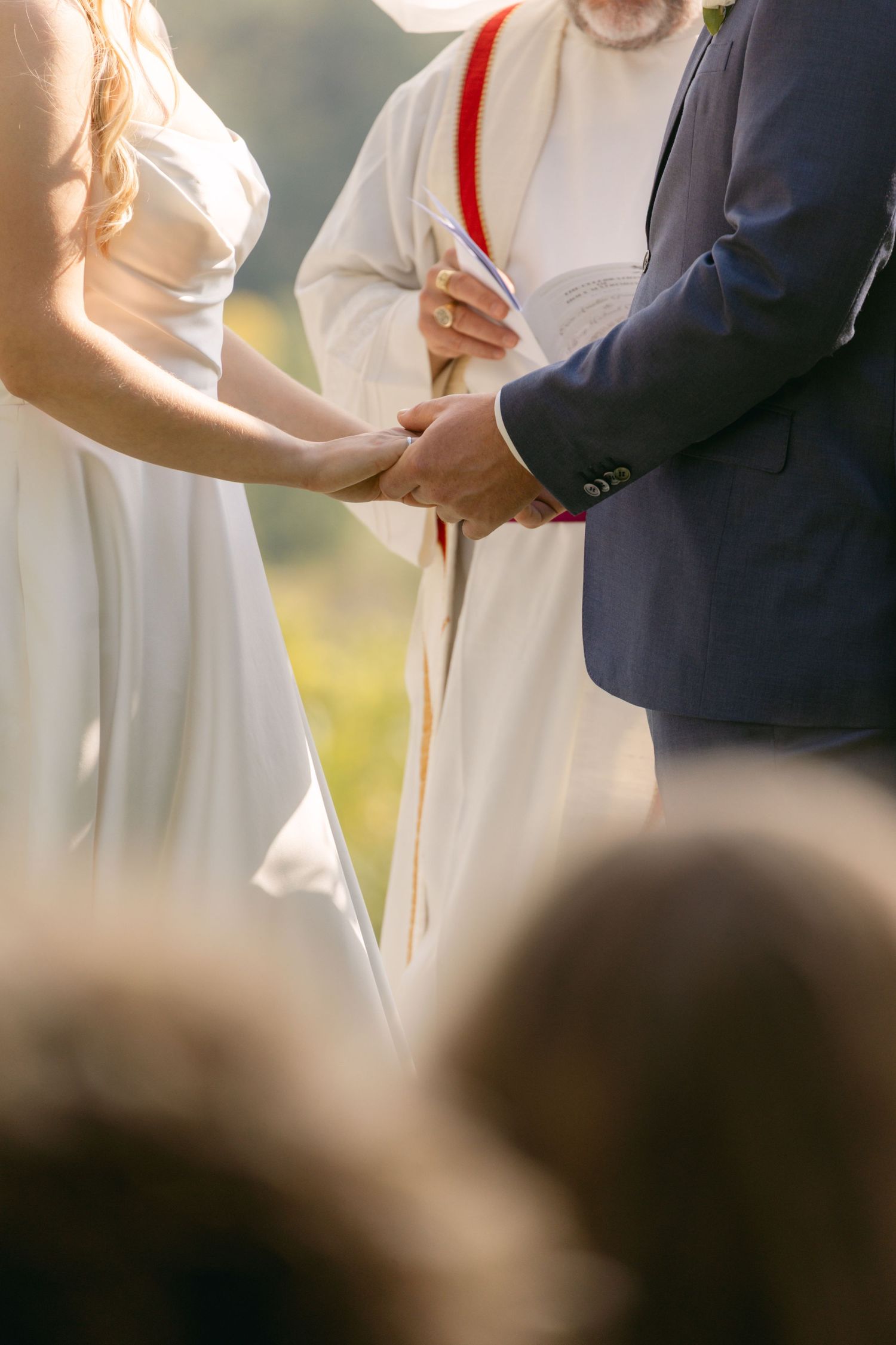 Close-up of formal attire and hands during wedding ceremony proceedings.