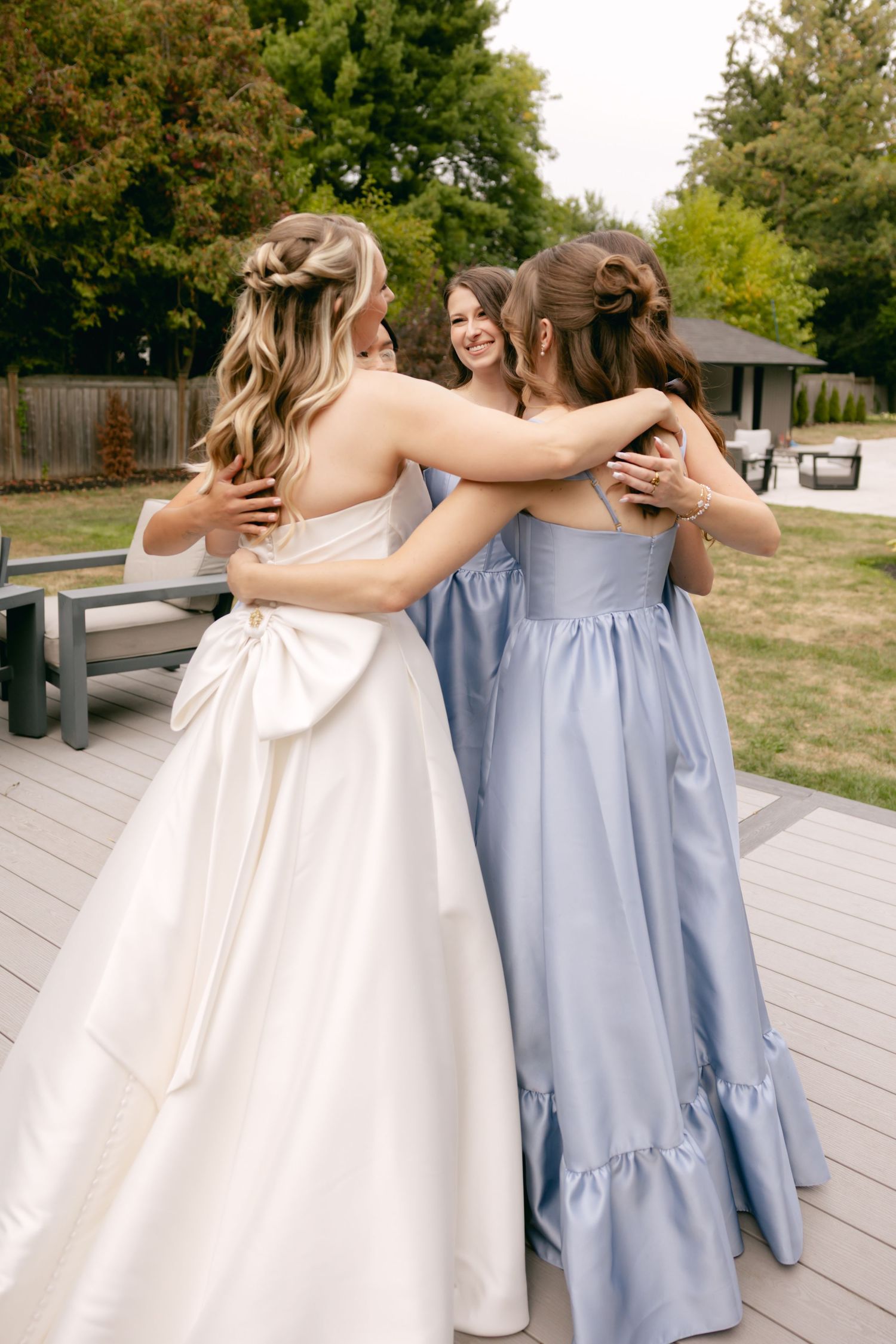 Wedding party embraces in a group hug wearing coordinated blue and white dresses.