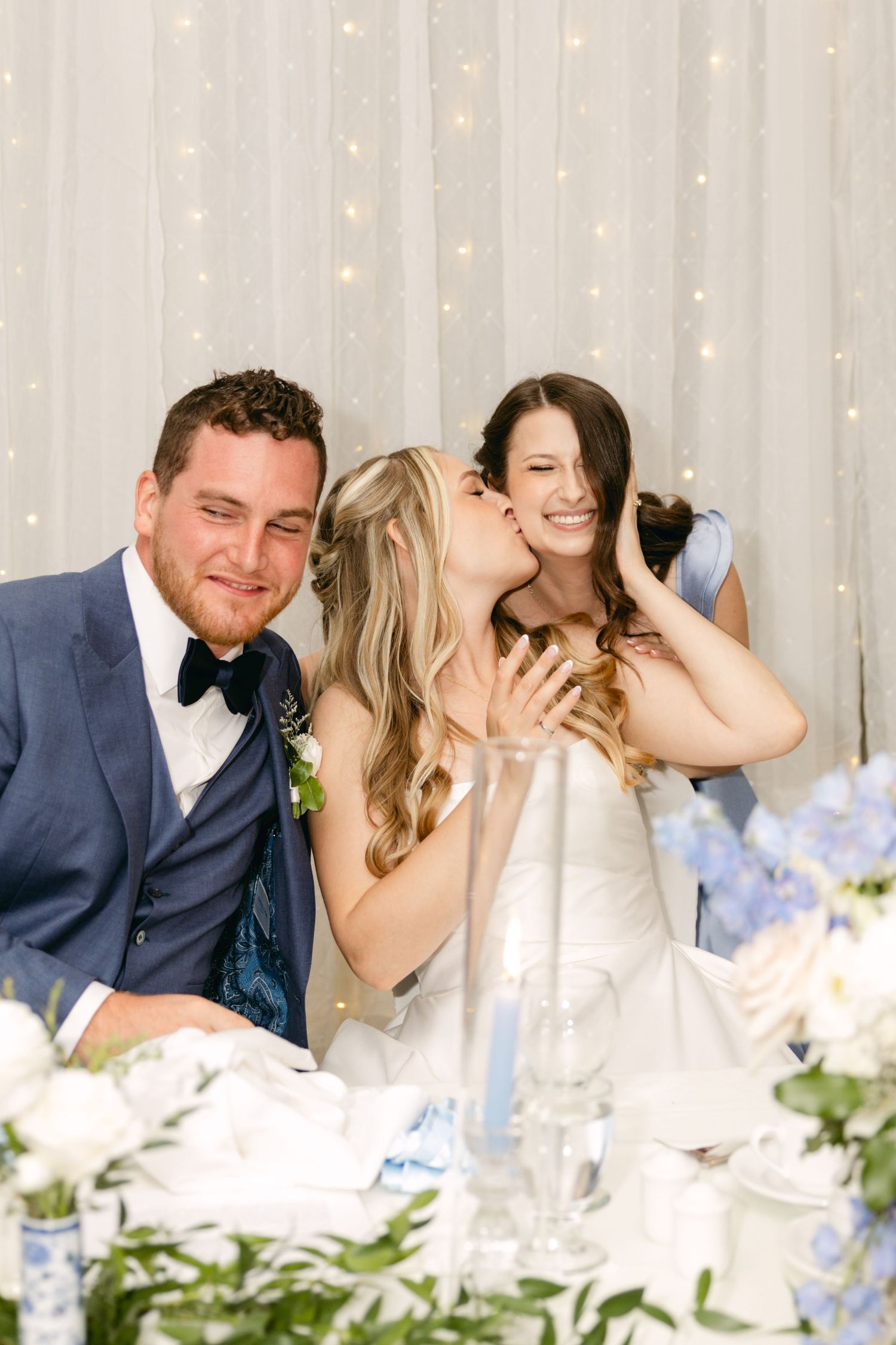 Intimate moment at wedding reception table with white and blue floral decorations.