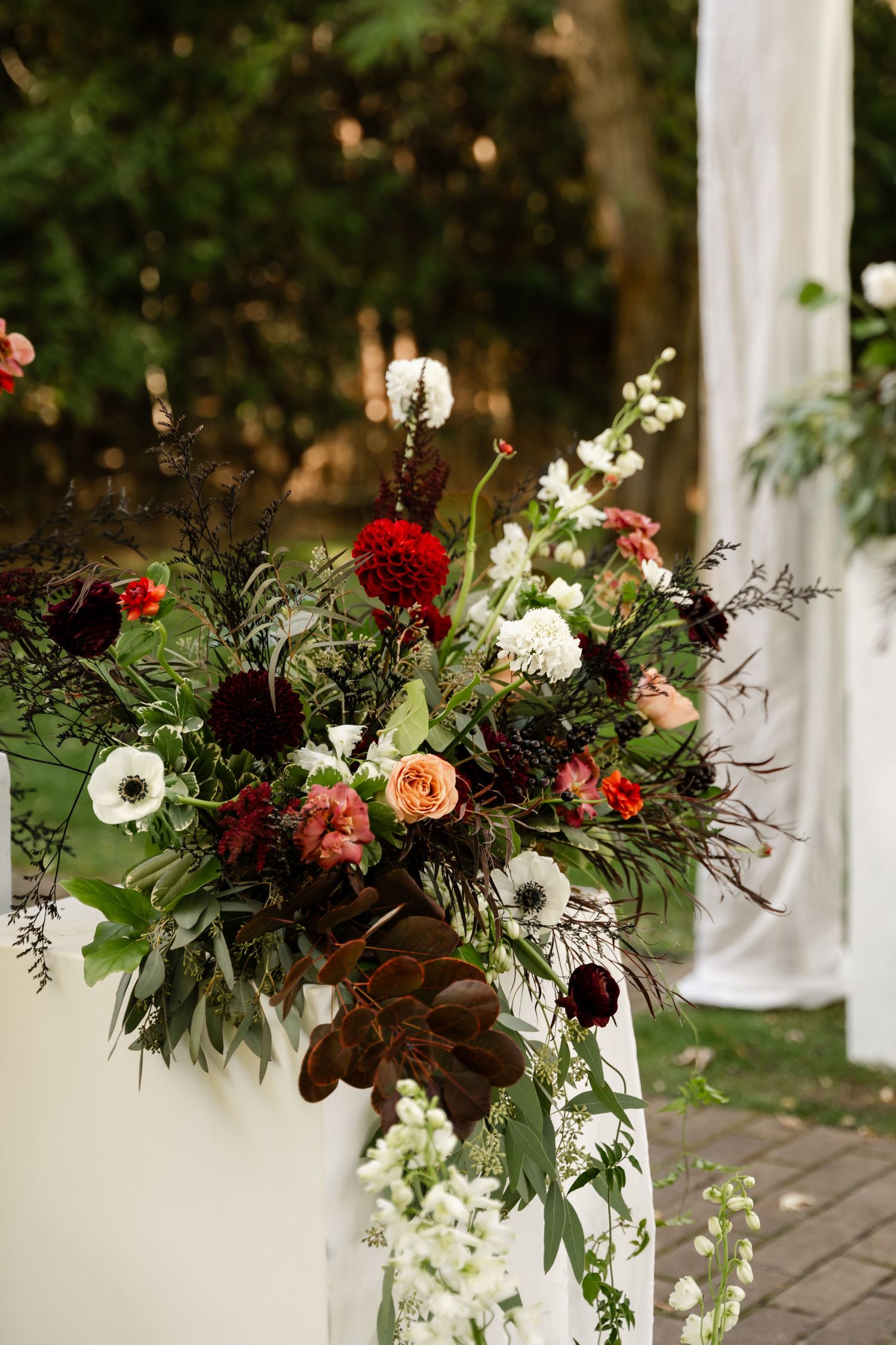 Elegant floral arrangement with red and white flowers decorating a white pillar.
