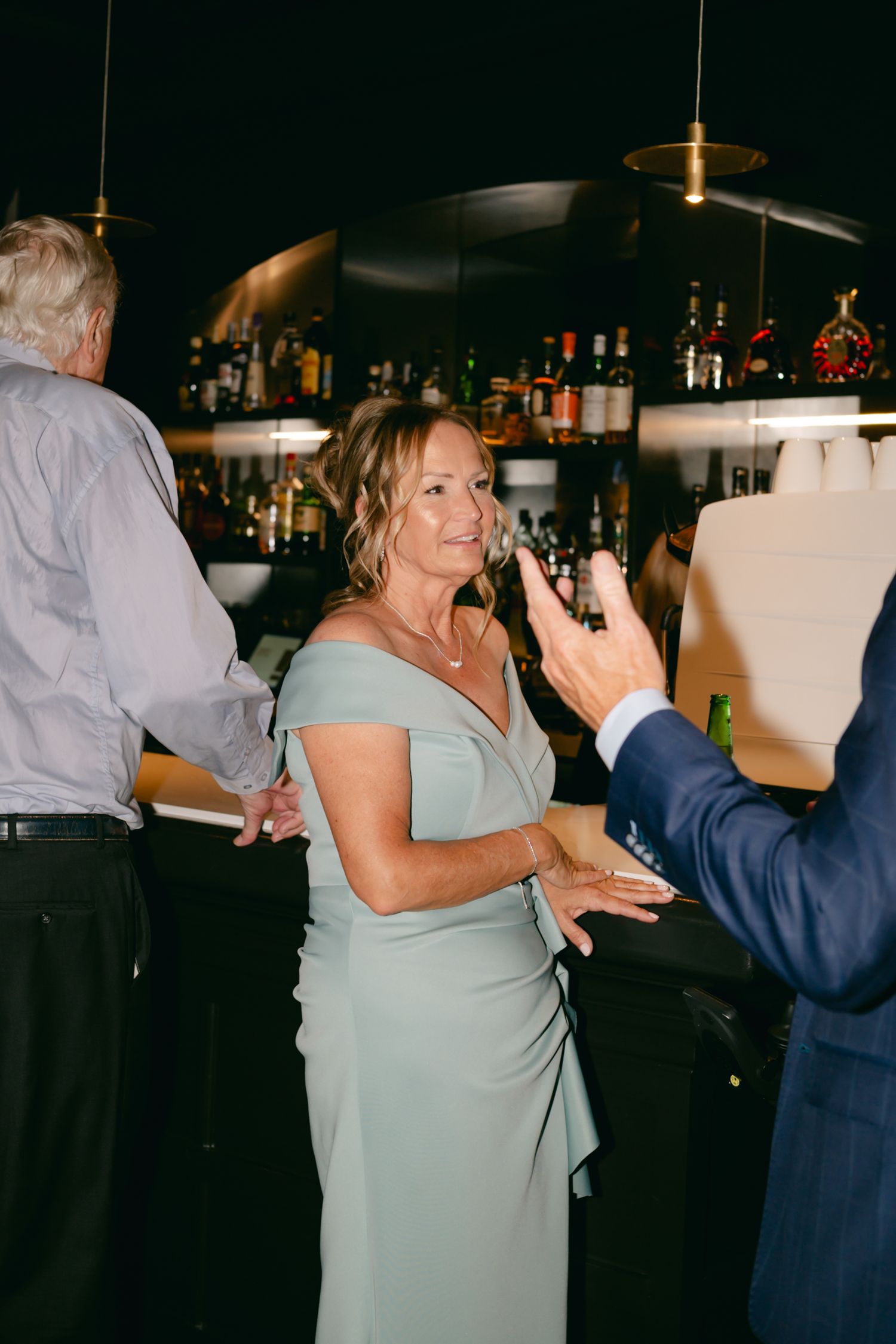 Guest in mint green dress dancing at wedding reception bar area.
