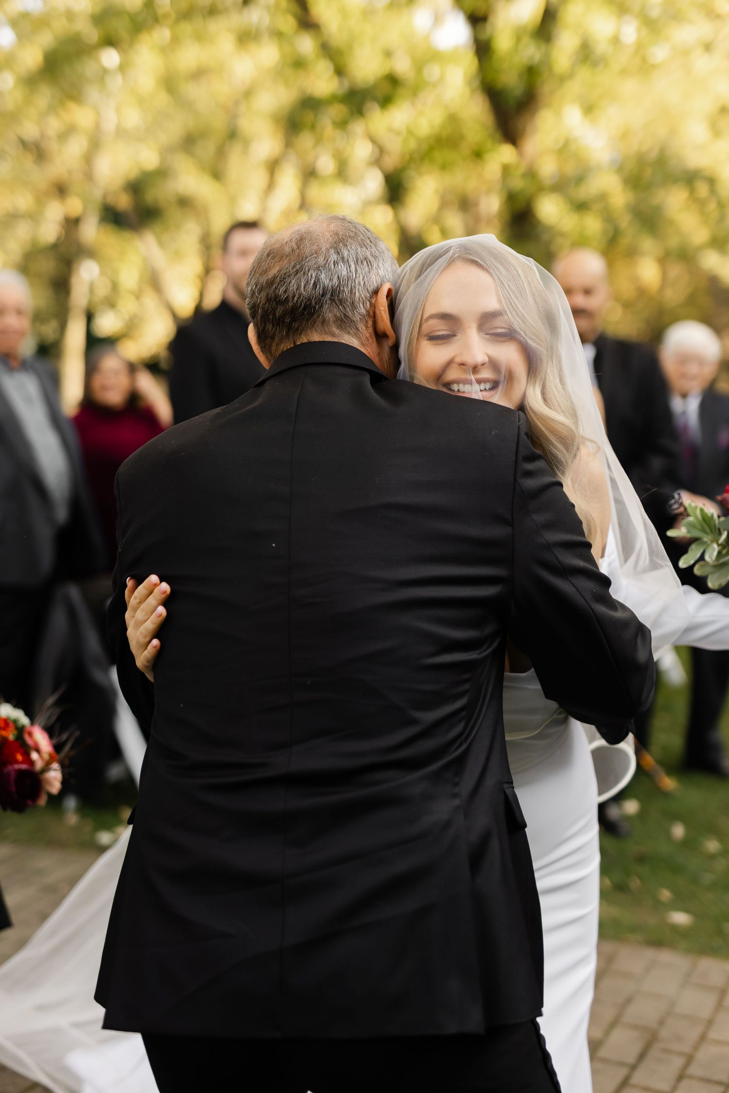Wedding guests embrace during an emotional outdoor celebration.