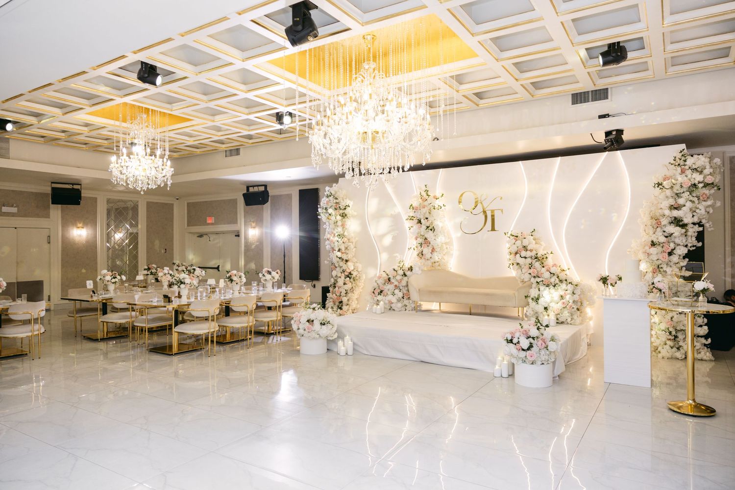 Luxurious white wedding venue with crystal chandeliers and elegant ceiling details.