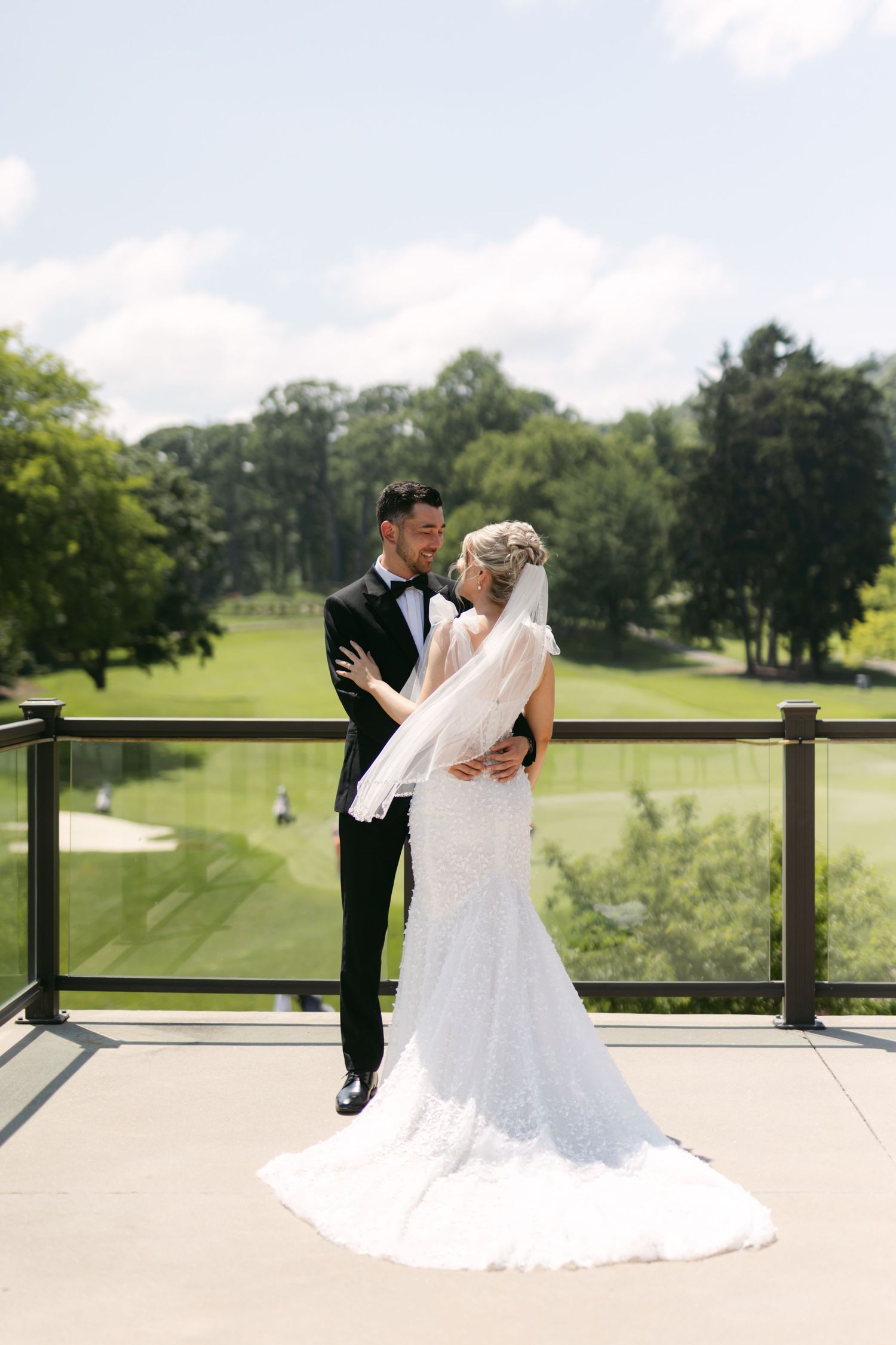 Couple shares romantic moment on sunny terrace overlooking lush golf course.