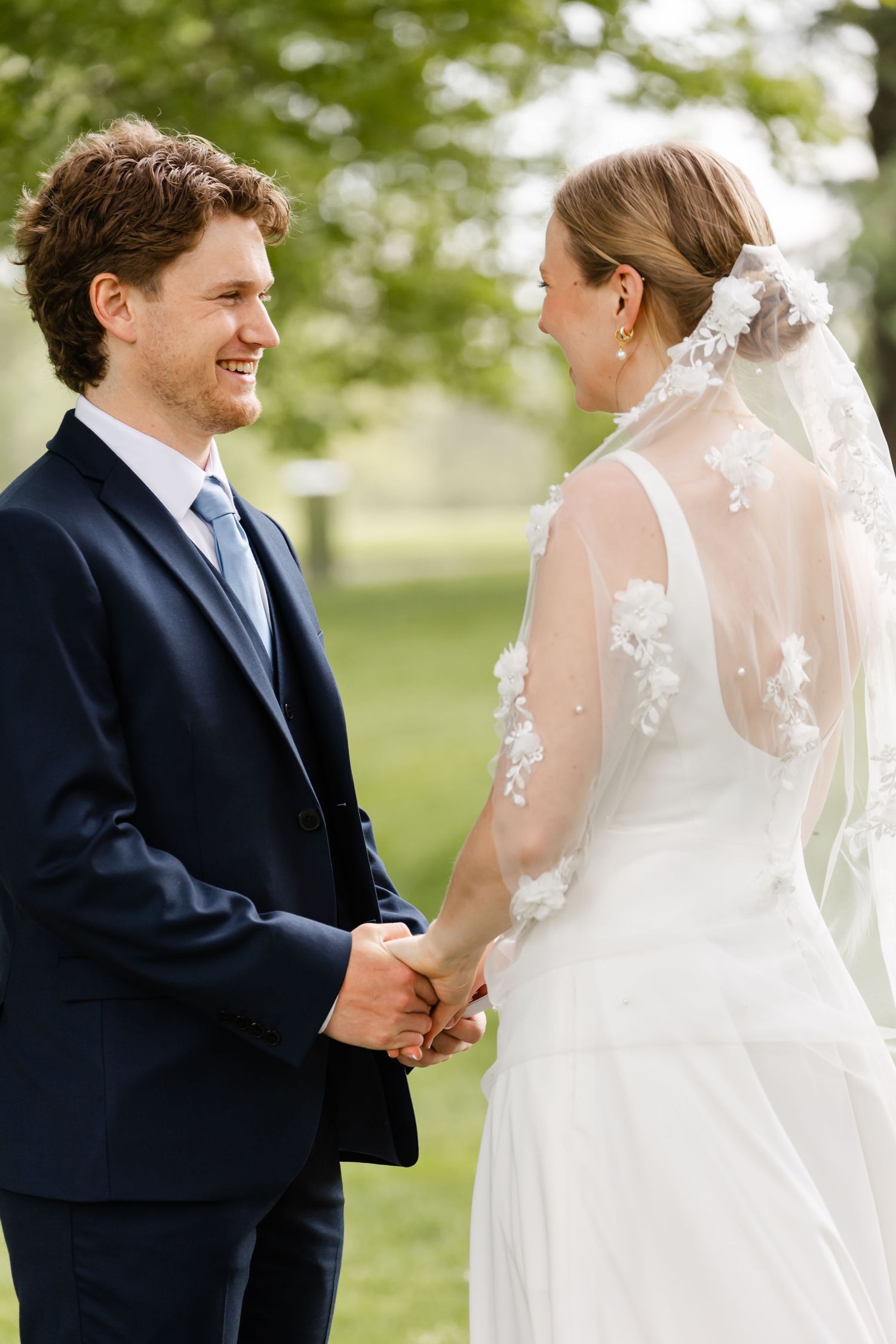 Intimate first look moment between couple in wedding attire outdoors.