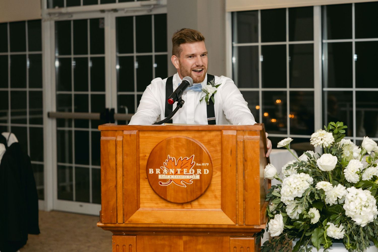 Wedding venue decorated with wooden podium and elegant white floral arrangements.