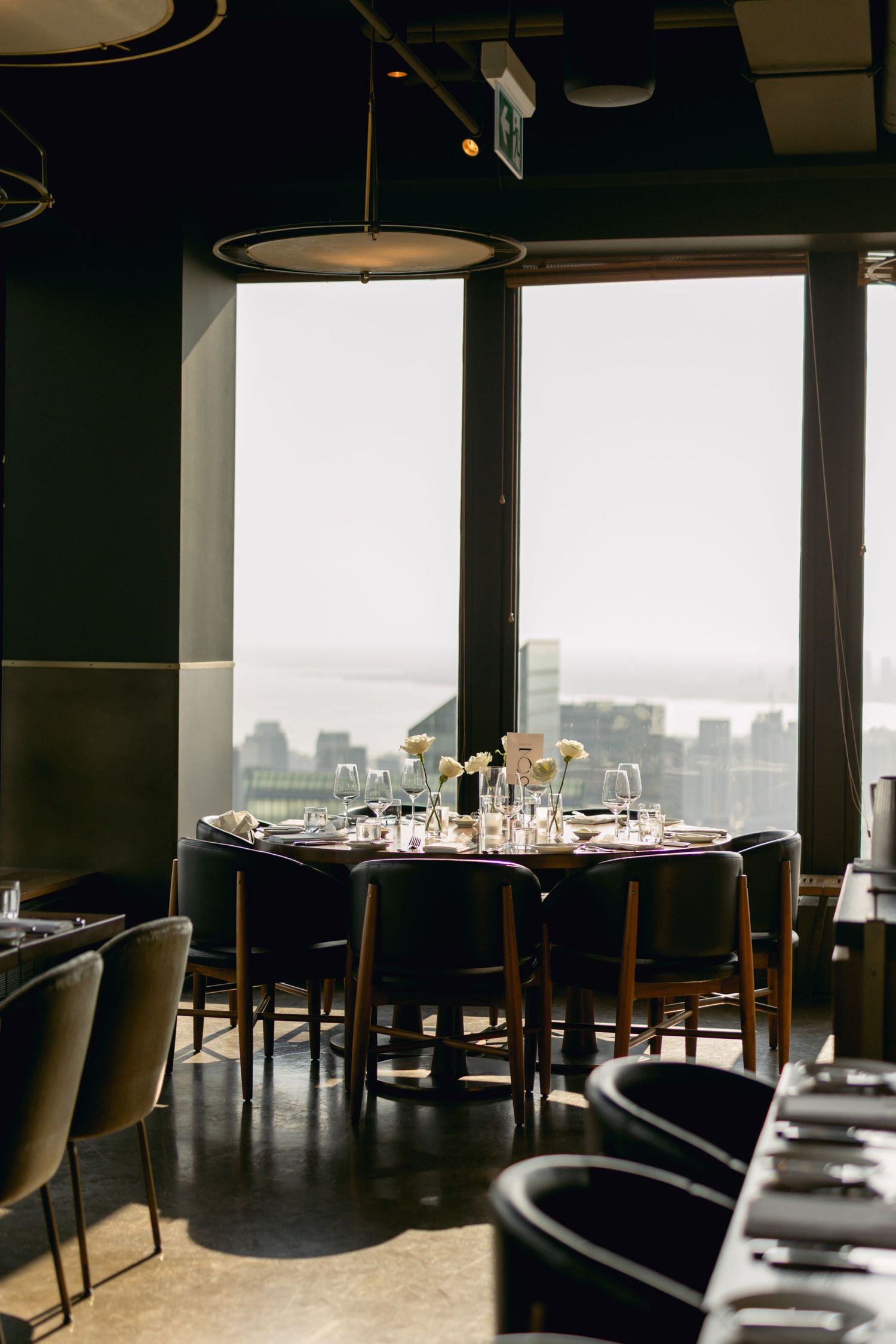 Elegant wedding reception table set near floor-to-ceiling windows with stunning city and water views.