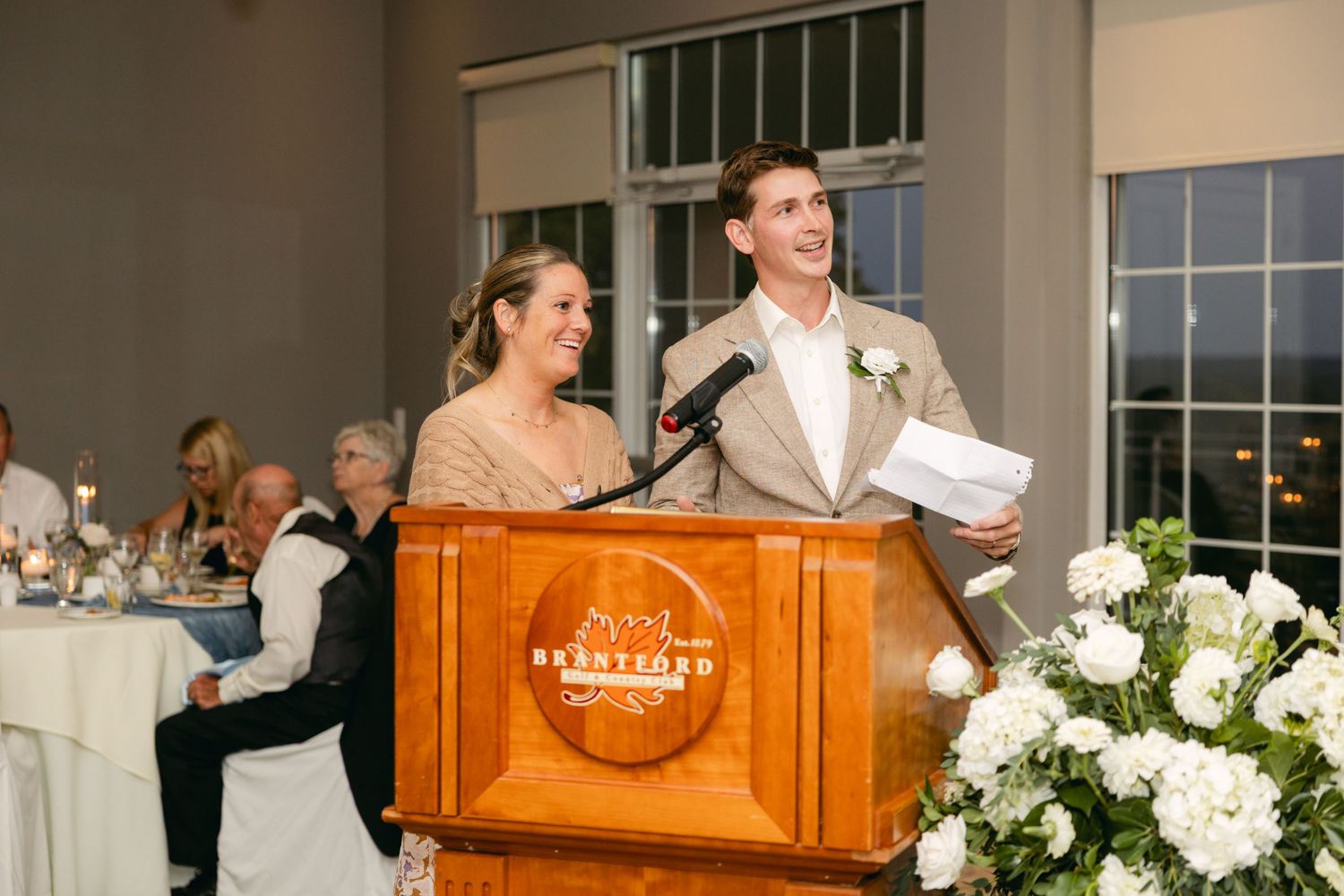 Elegant wedding venue setup with wooden podium and white floral decorations.