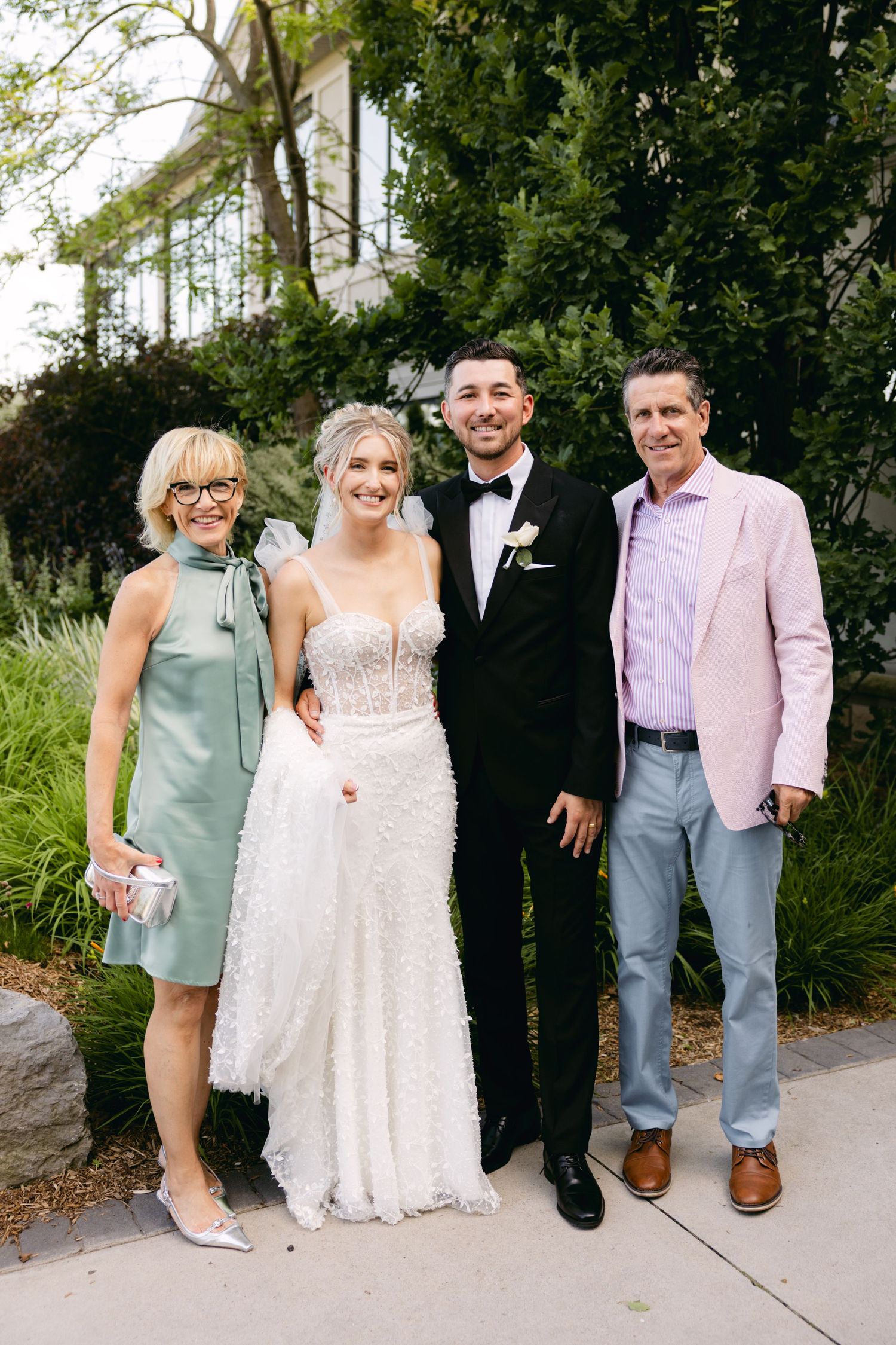 Wedding party members pose in pastel and formal attire on outdoor path.
