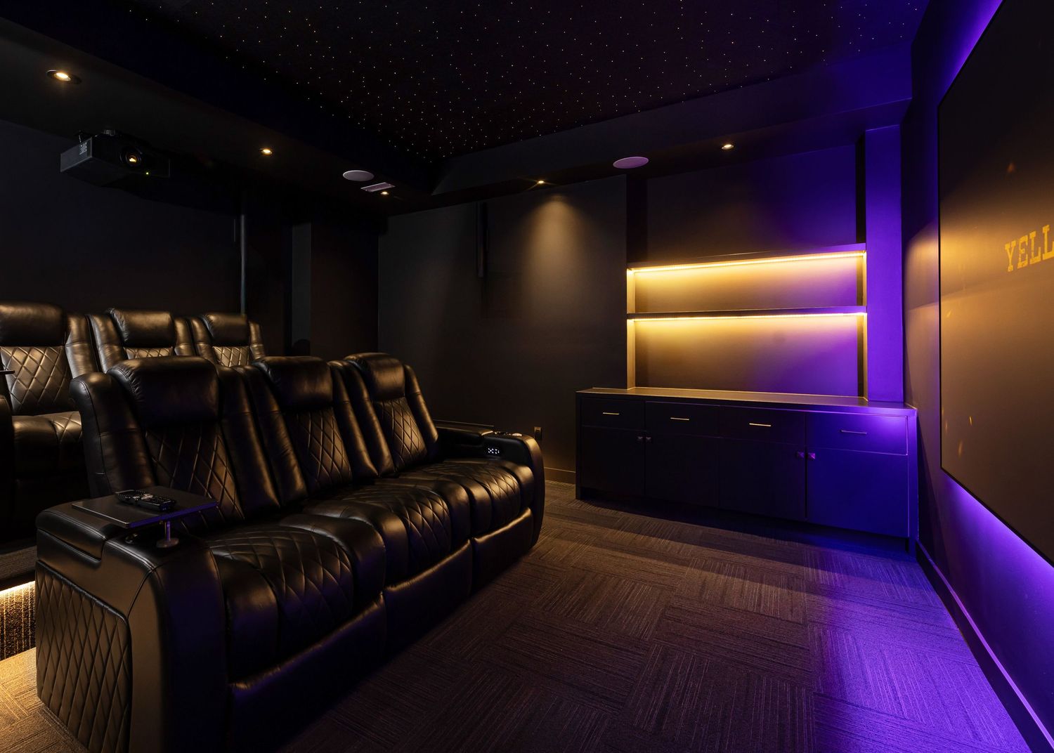 Theater room features dark walls with purple ambient lighting and comfortable reclining seats.