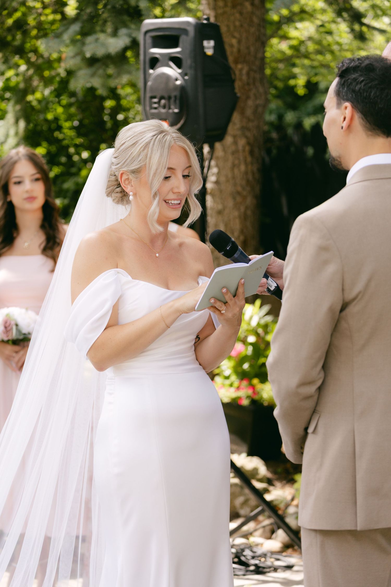 Wedding party members share candid reactions during a first look moment in a garden setting.