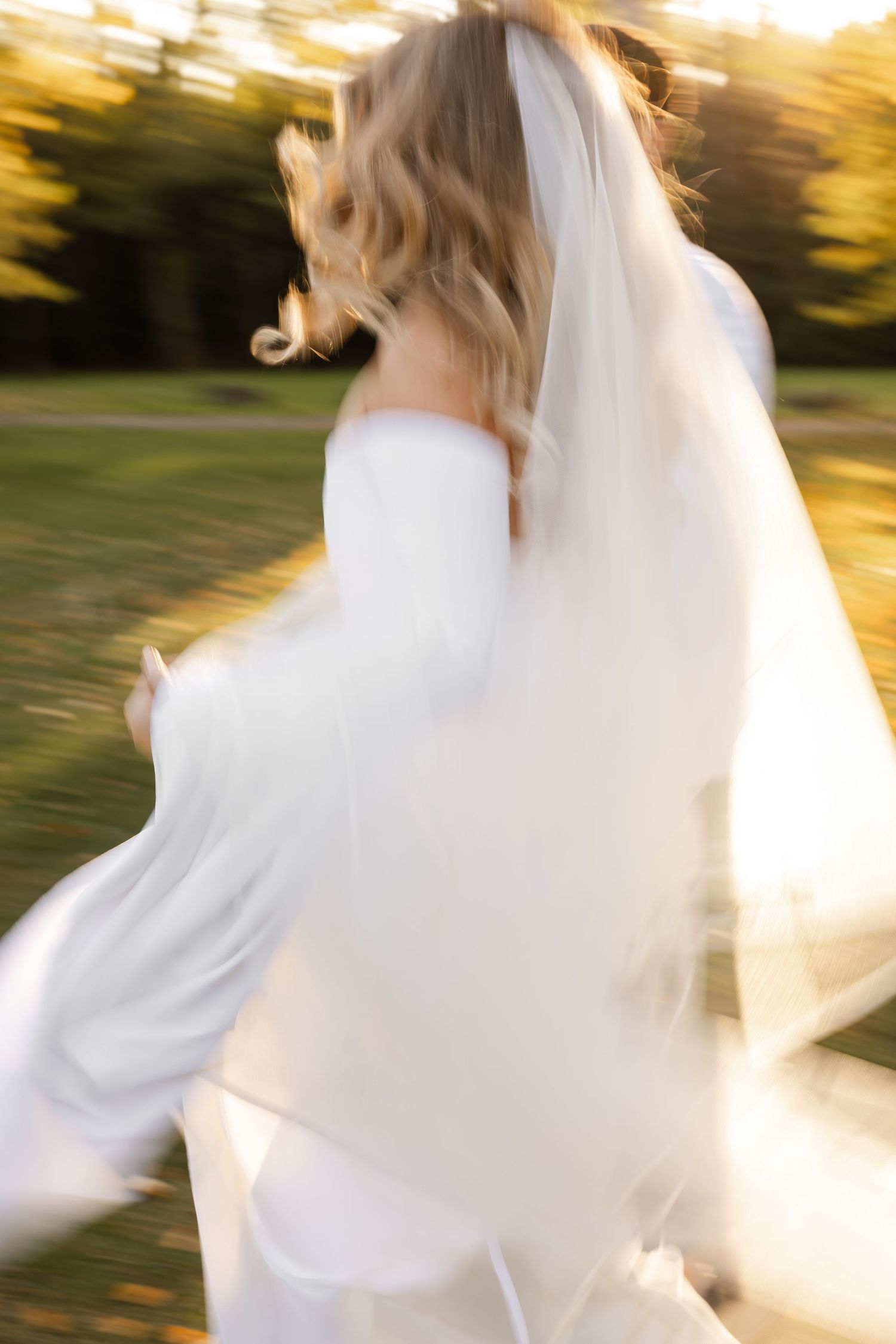 Motion-blur wedding photo of bride spinning in white dress during golden hour.