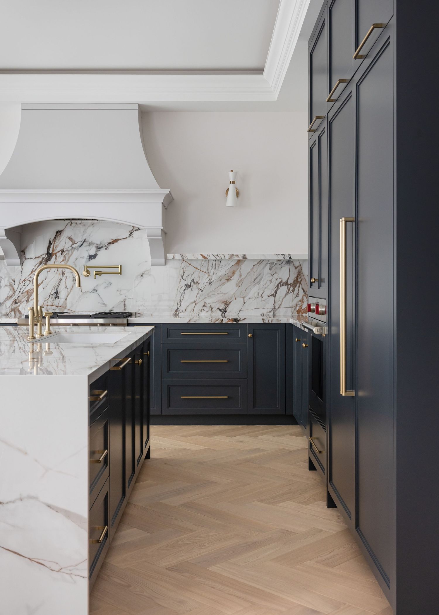 Elegant kitchen with navy blue cabinets, marble countertops, and brass fixtures.