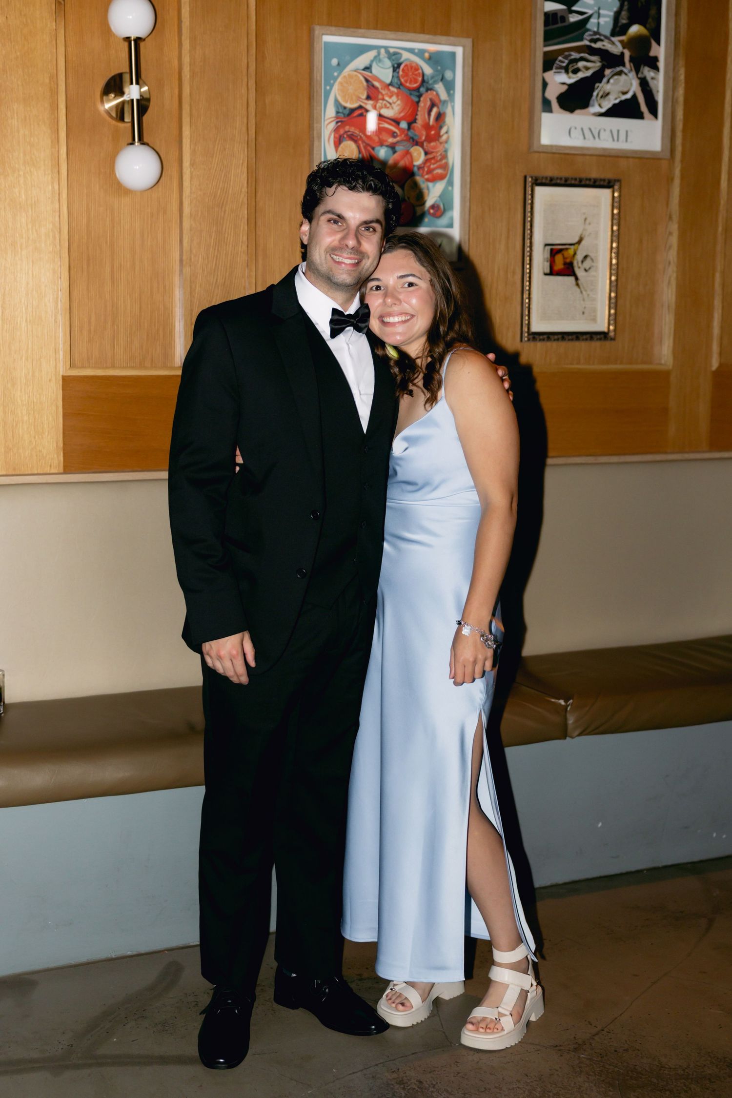 Couple smiling together at a wedding reception, woman in light blue gown and man in tuxedo.