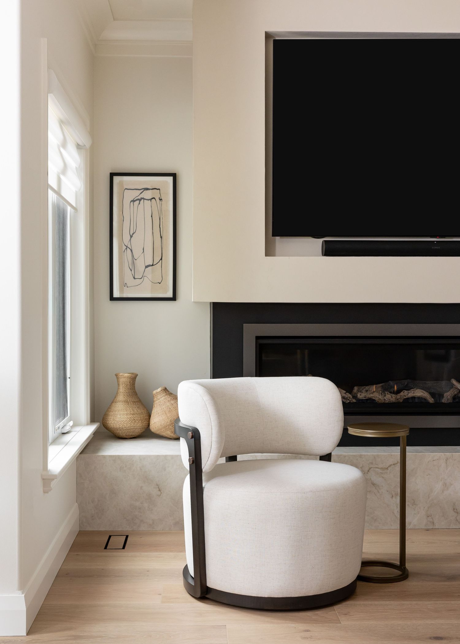 Contemporary living space featuring white curved seating and a sleek black fireplace against white walls.
