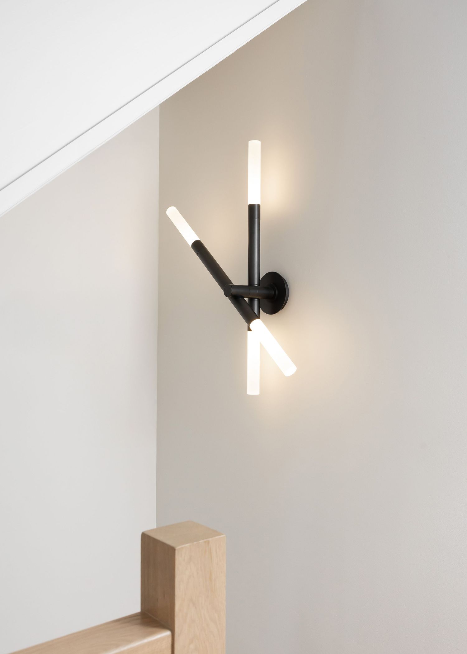 Minimalist wall sconce with angled black and white design mounted on light colored wall.