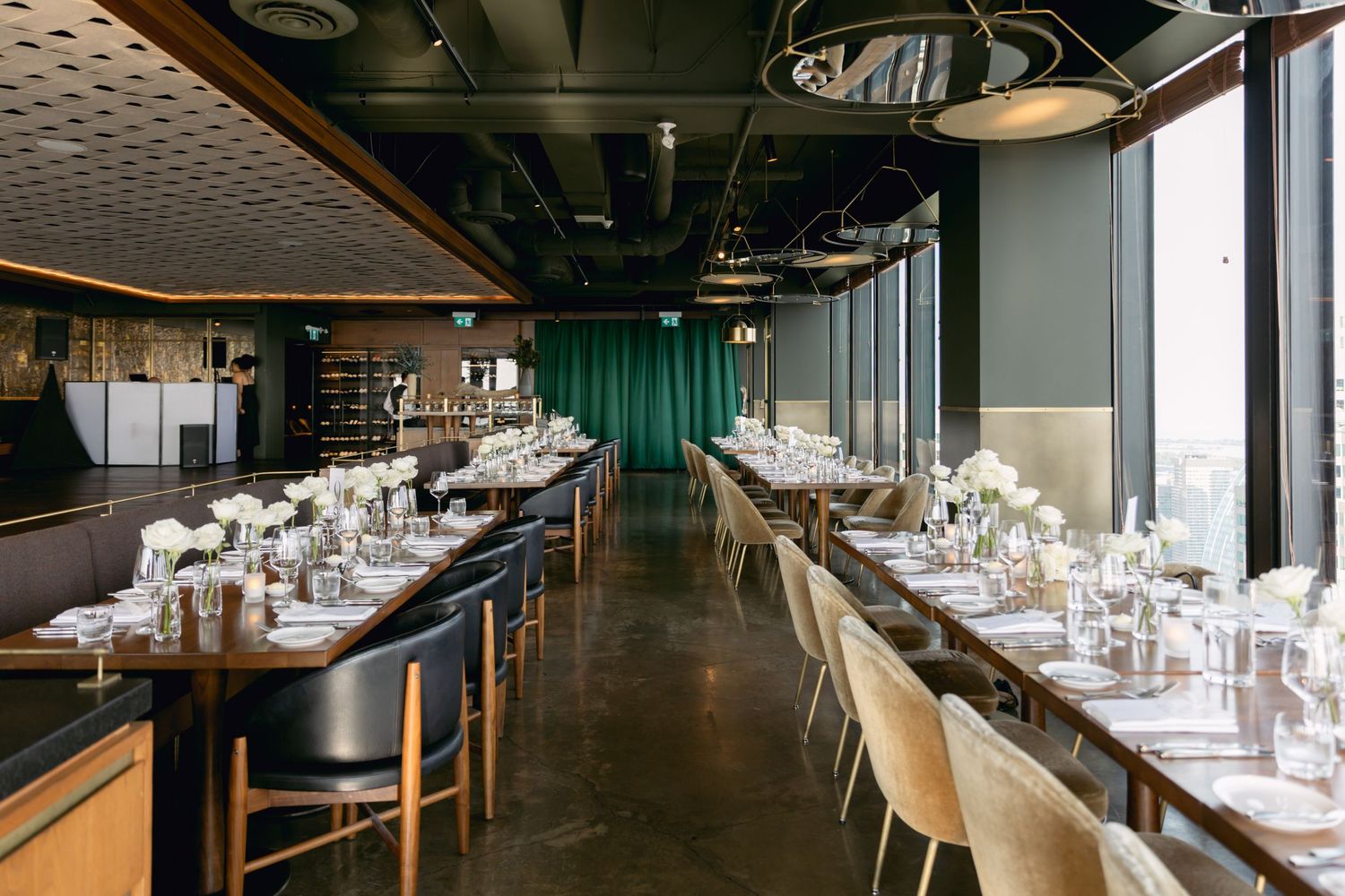 Elegant wedding reception venue with long dining tables, white floral centerpieces, and emerald green accents.