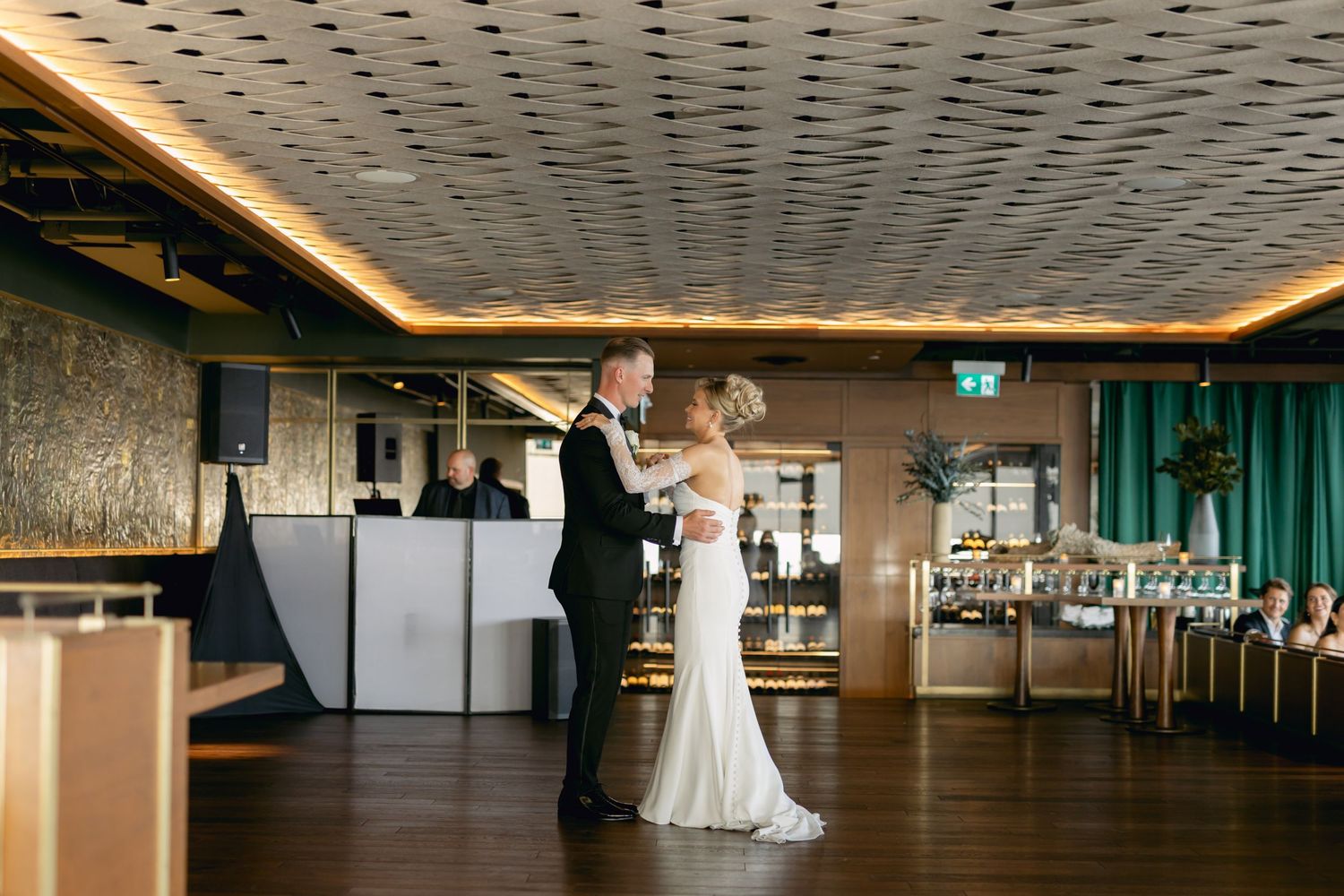 Bride and groom share their first dance in a modern reception venue with warm ambient lighting.