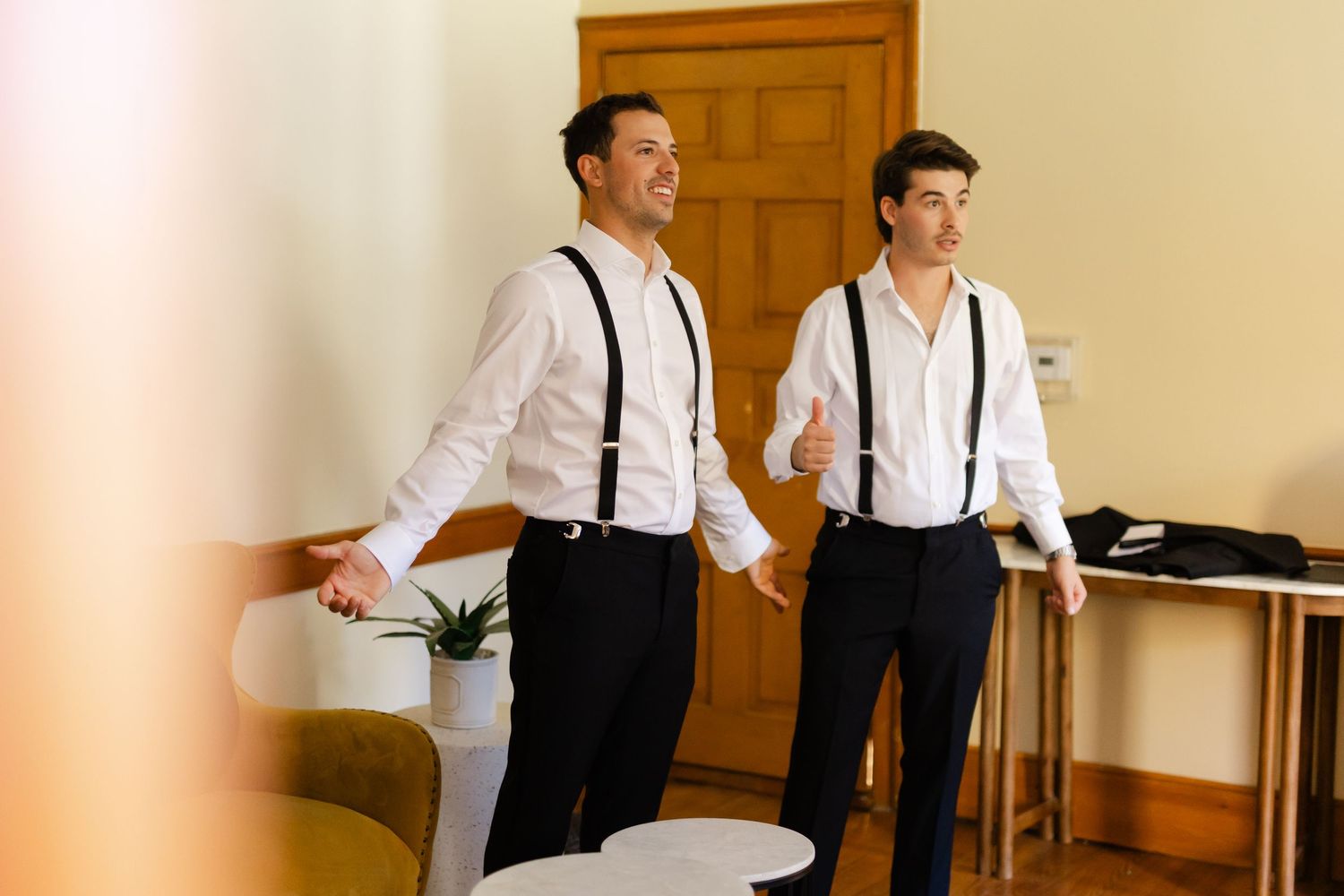 Groomsmen in white shirts and suspenders preparing for wedding ceremony.
