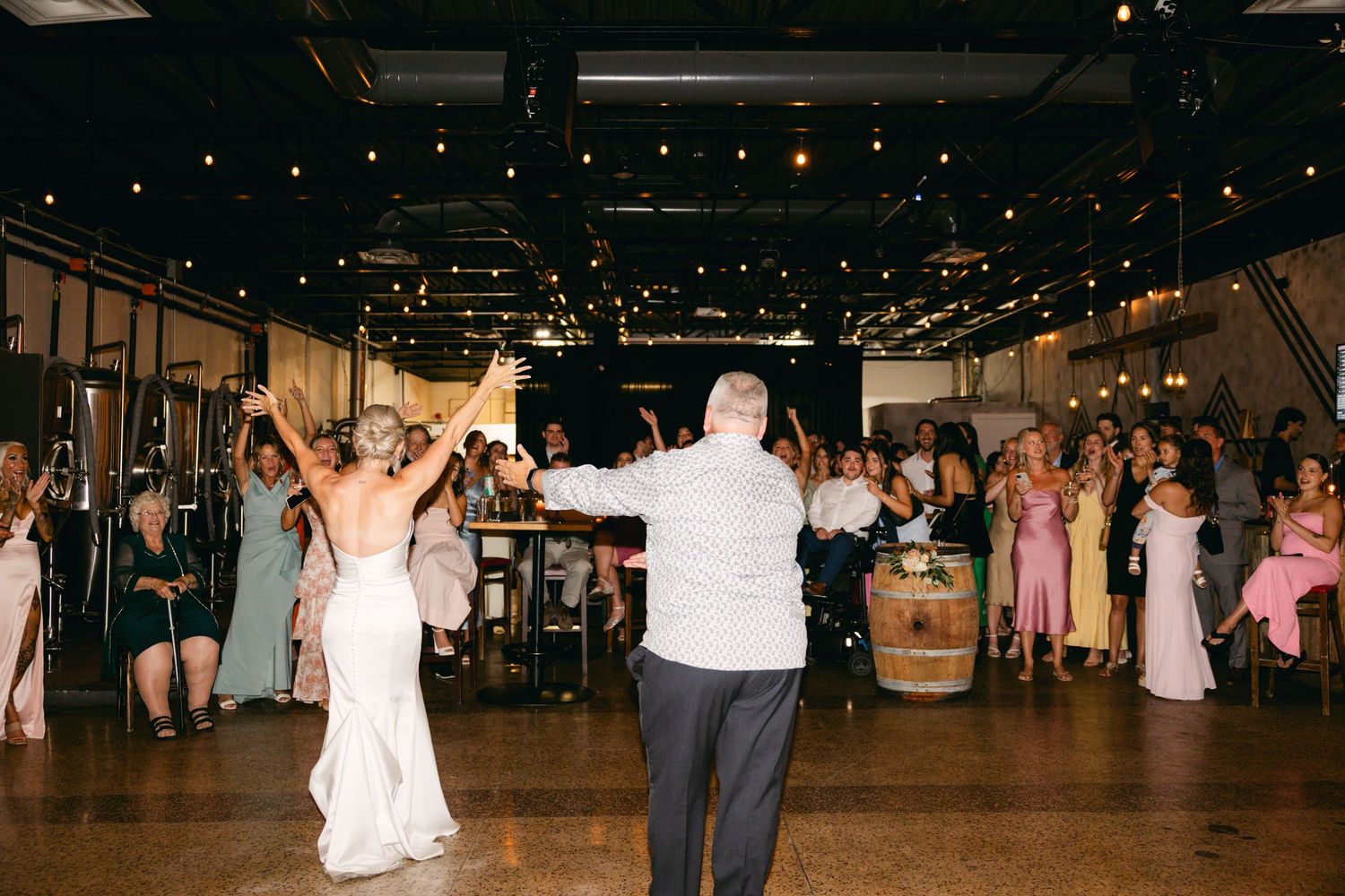 Wedding reception dance floor filled with couples dancing under sparkling string lights.