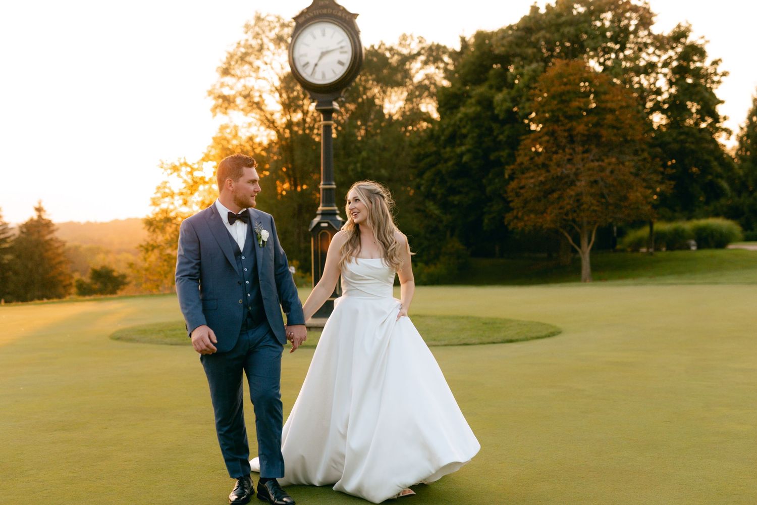 Sunset wedding photos on rolling golf course greens with decorative clock feature.
