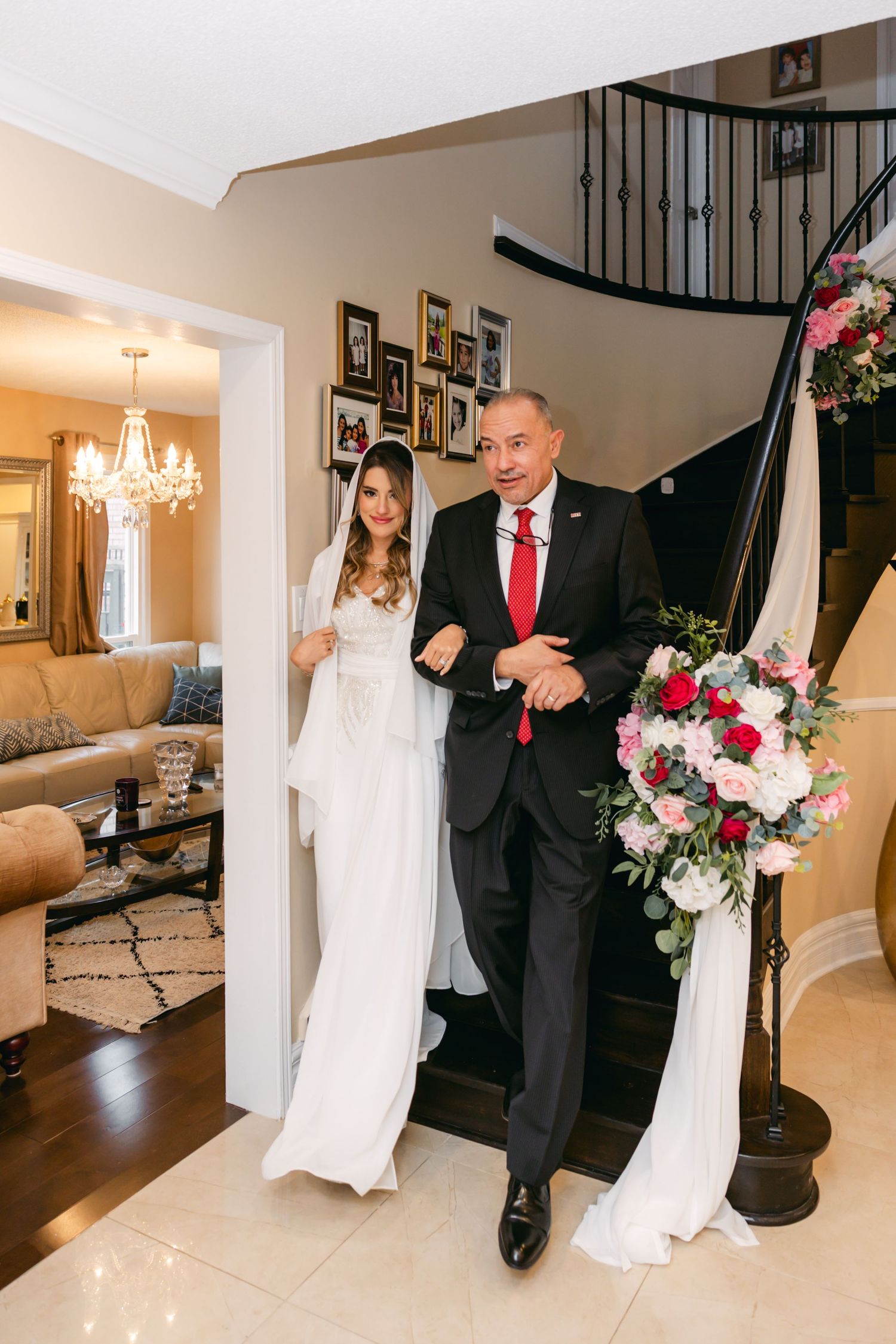 Elegant indoor wedding photos taken on a staircase with pink floral accents and chandeliers.