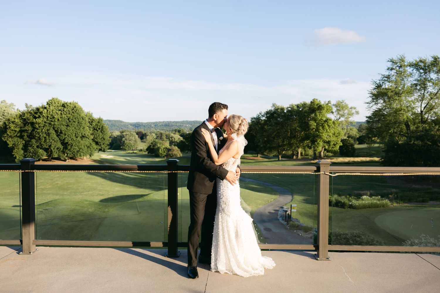 Panoramic view of a wedding venue's outdoor terrace with rolling green hills in the background.