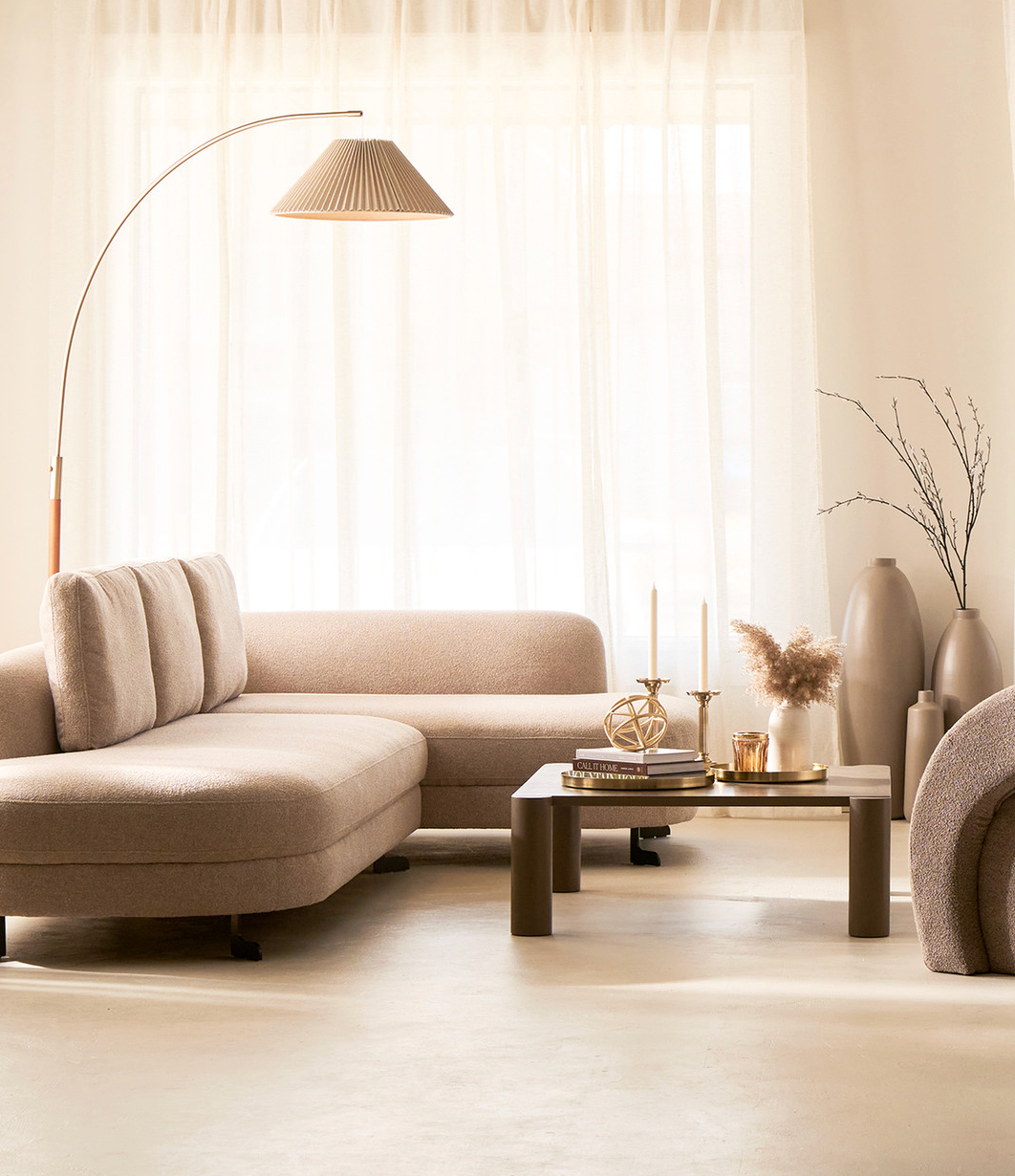 Modern minimalist spa waiting room with curved beige loungers and pendant lighting in a serene neutral setting.