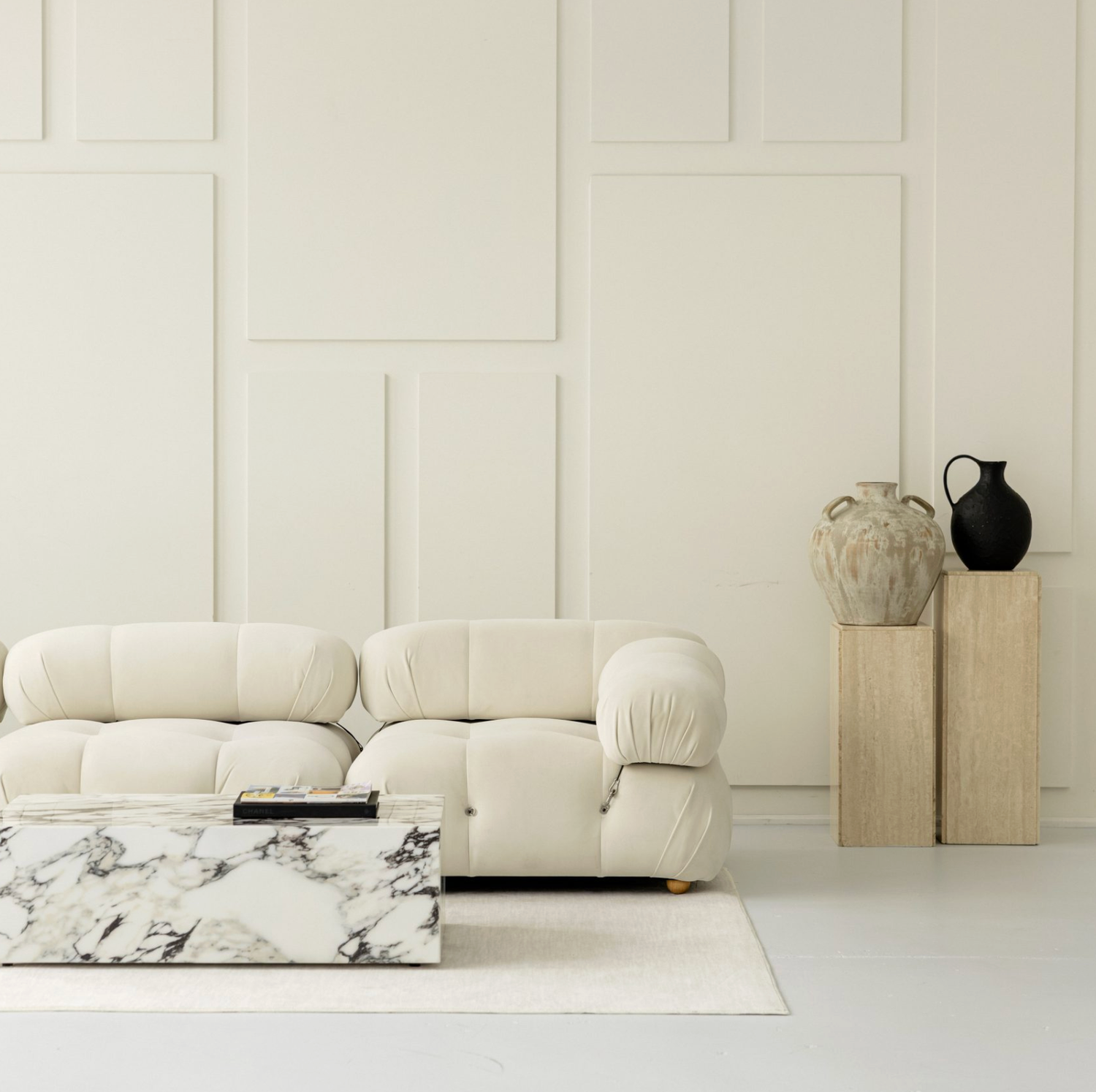Minimalist white interior design space featuring modular seating and marble accents against a bright white backdrop.