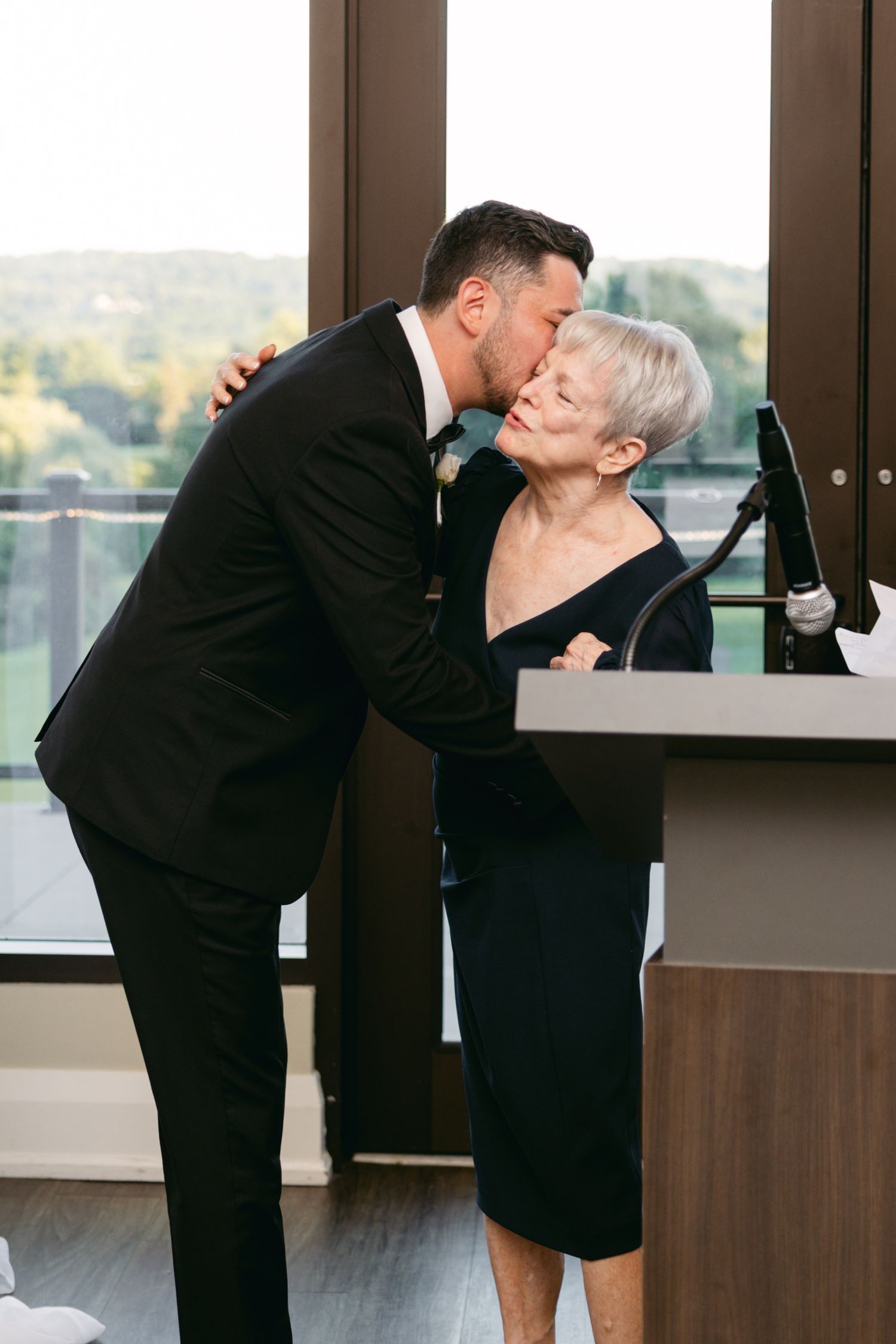 Sweet moment captured during wedding reception in venue with panoramic windows.