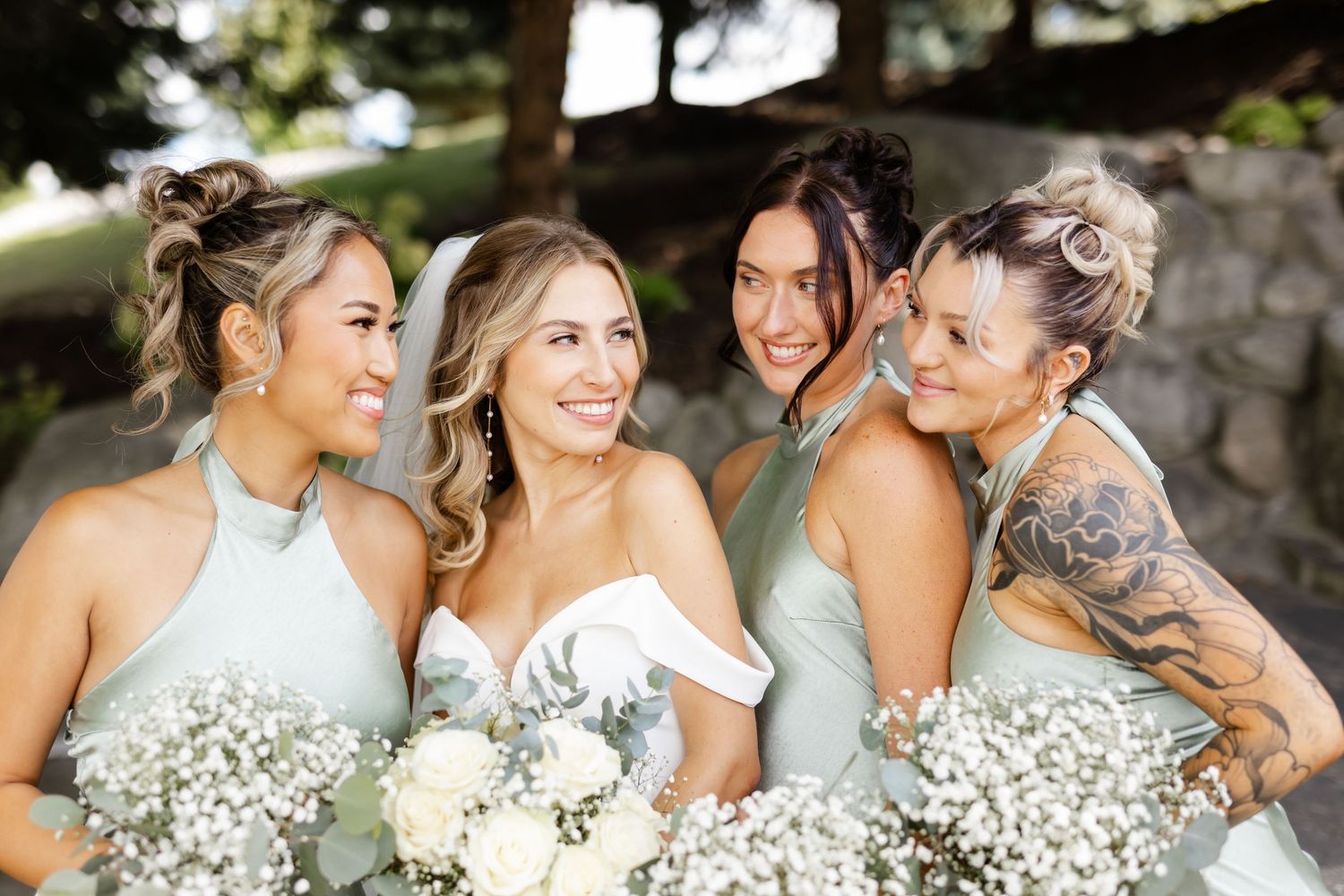 Bridesmaids in mint green dresses sharing joyful moments with bride outdoors.