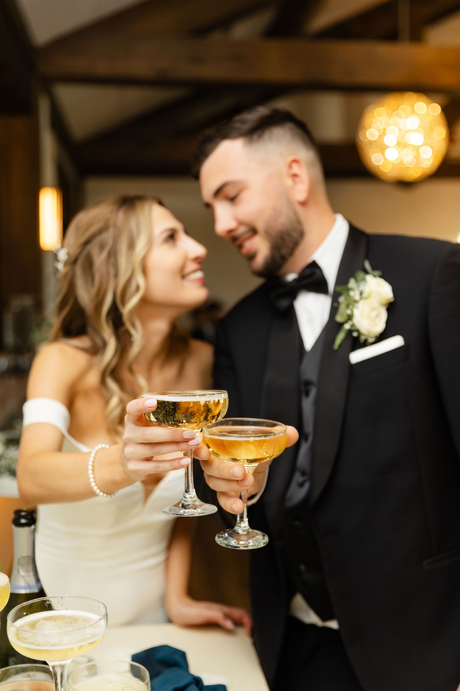 Couple in formal attire sharing champagne and intimate moments at their wedding reception.