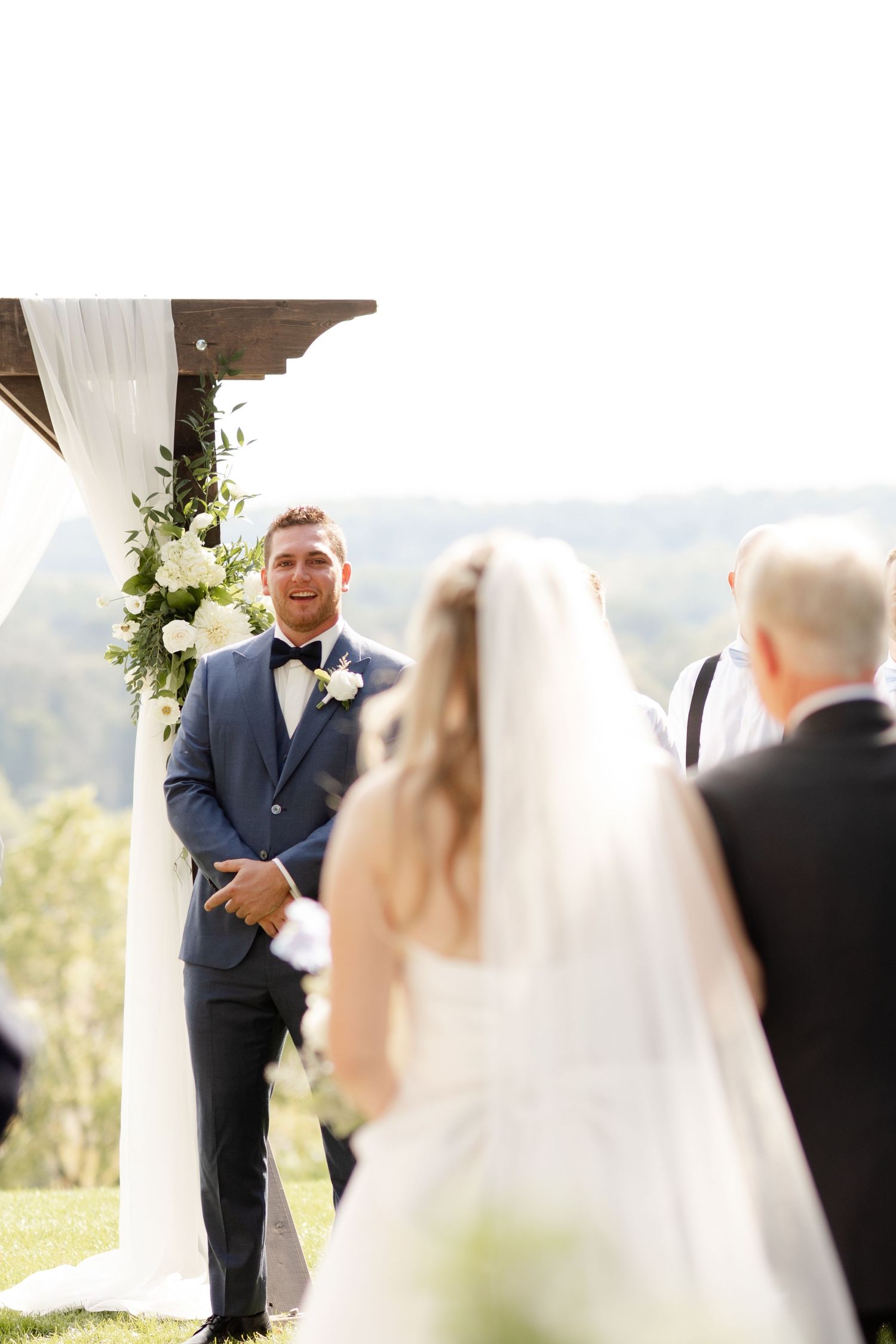 Wedding ceremony moment captured at outdoor venue with scenic backdrop.