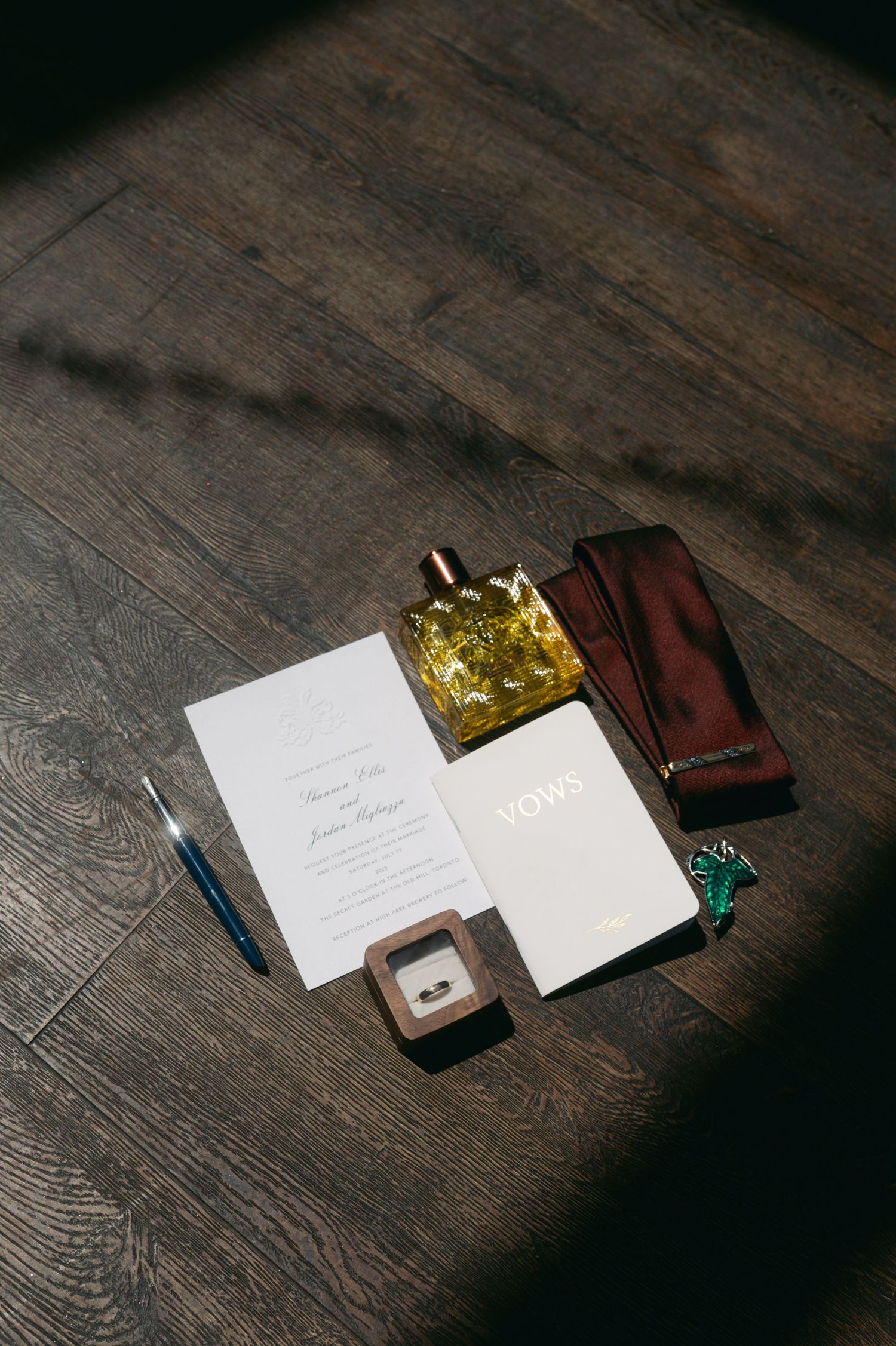 Wedding stationery and vow books arranged on dark wooden surface with dramatic lighting.