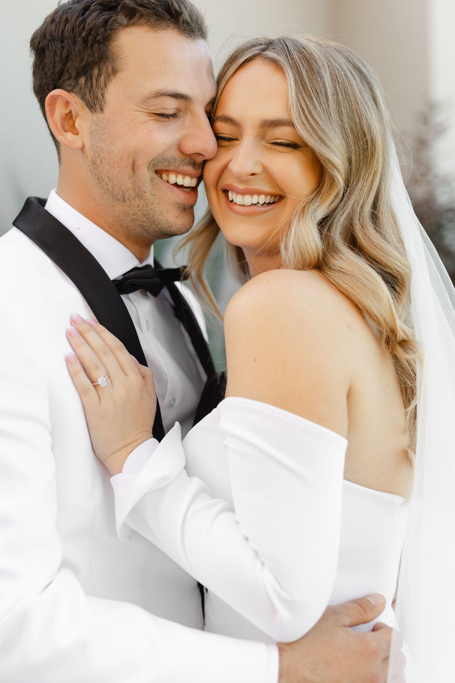 Joyful wedding portrait of a couple in formal attire sharing an intimate moment with bright smiles.