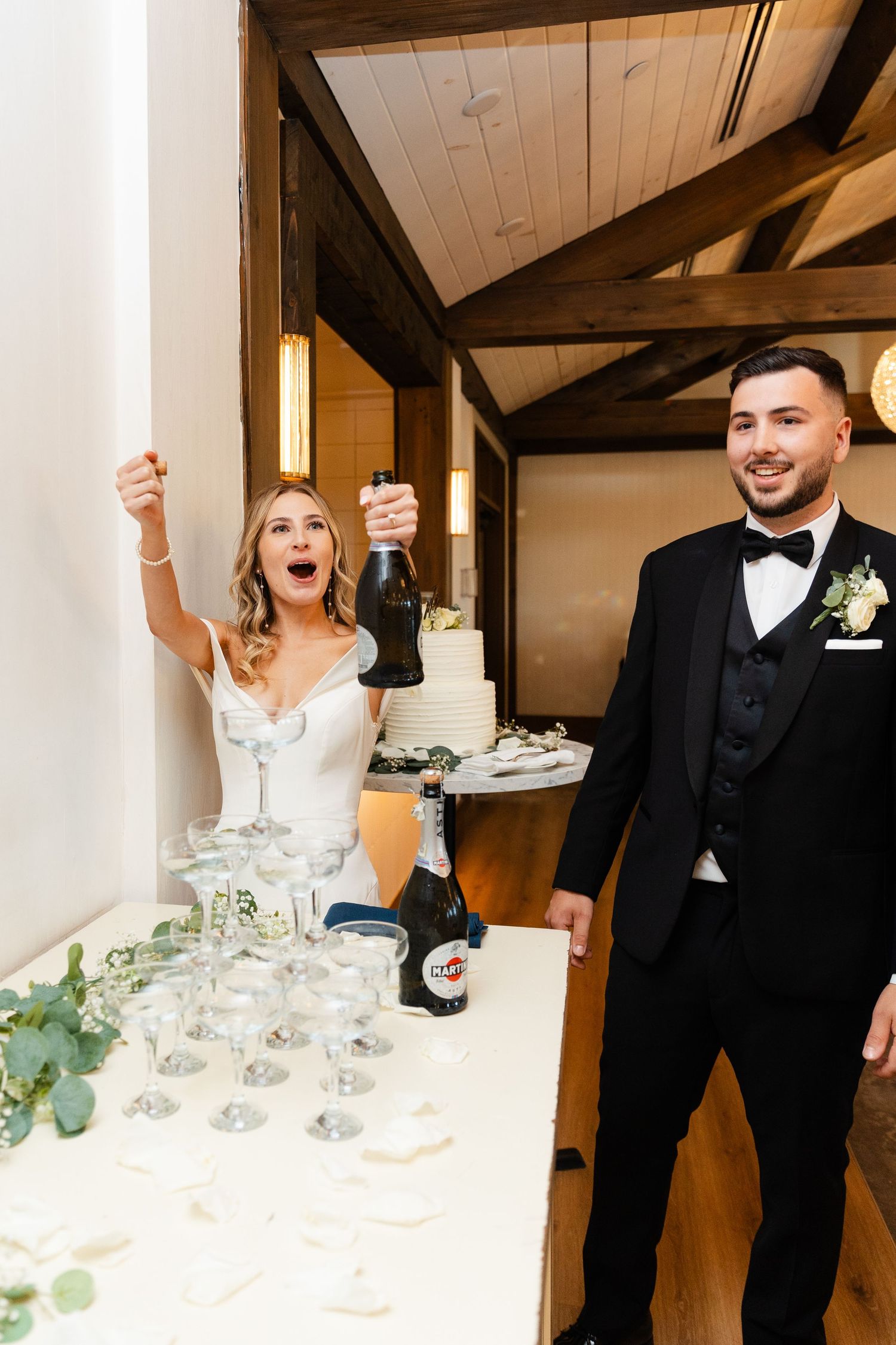 Wedding celebration moment at champagne table with rustic wood beam ceiling.
