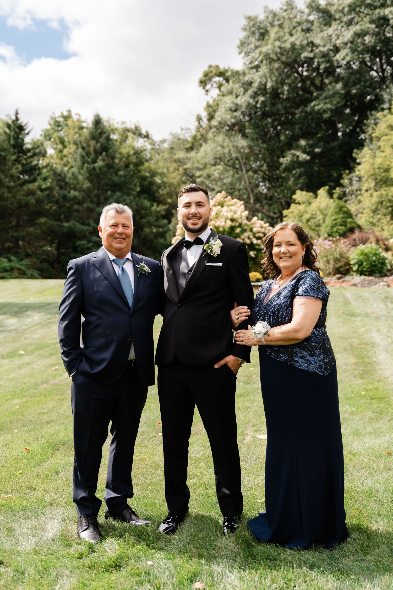 Family members in formal attire posing together outdoors for wedding photos.