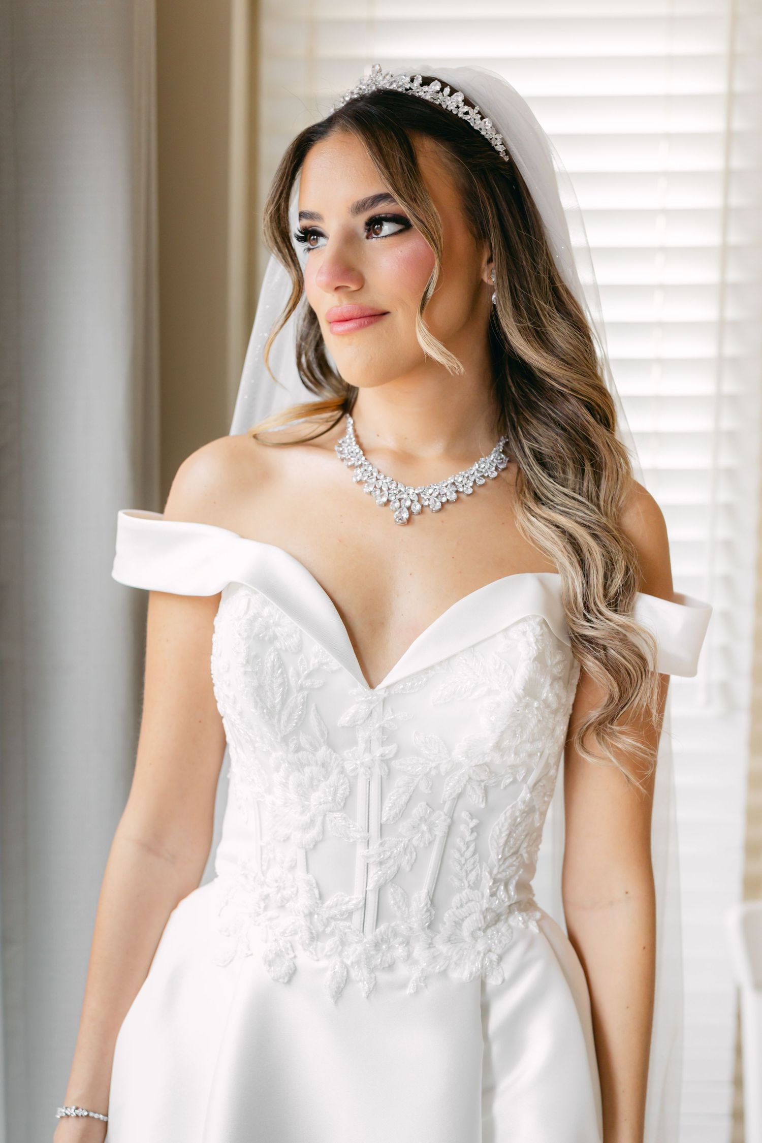 Elegant bridal portrait showing detailed white wedding dress and sparkling jewelry.