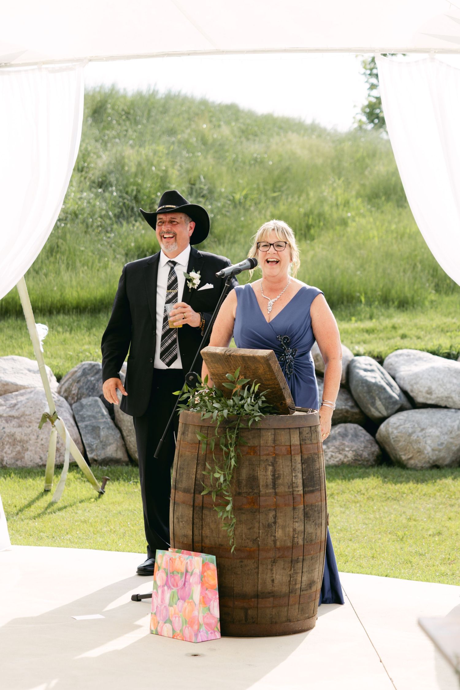 Wedding performers stand behind rustic wooden barrels during an outdoor ceremony.