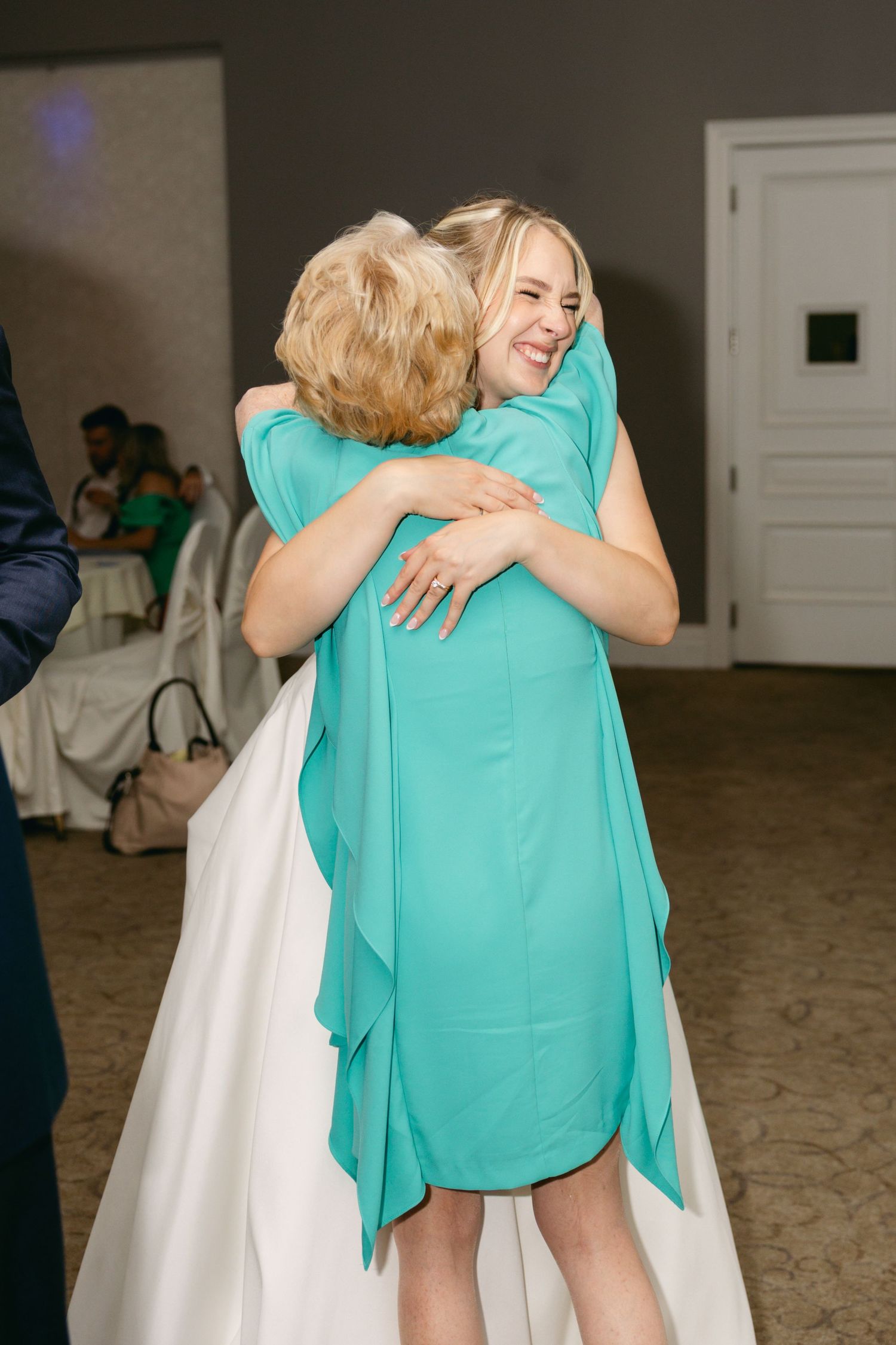 Wedding guests sharing warm embrace at reception celebration.