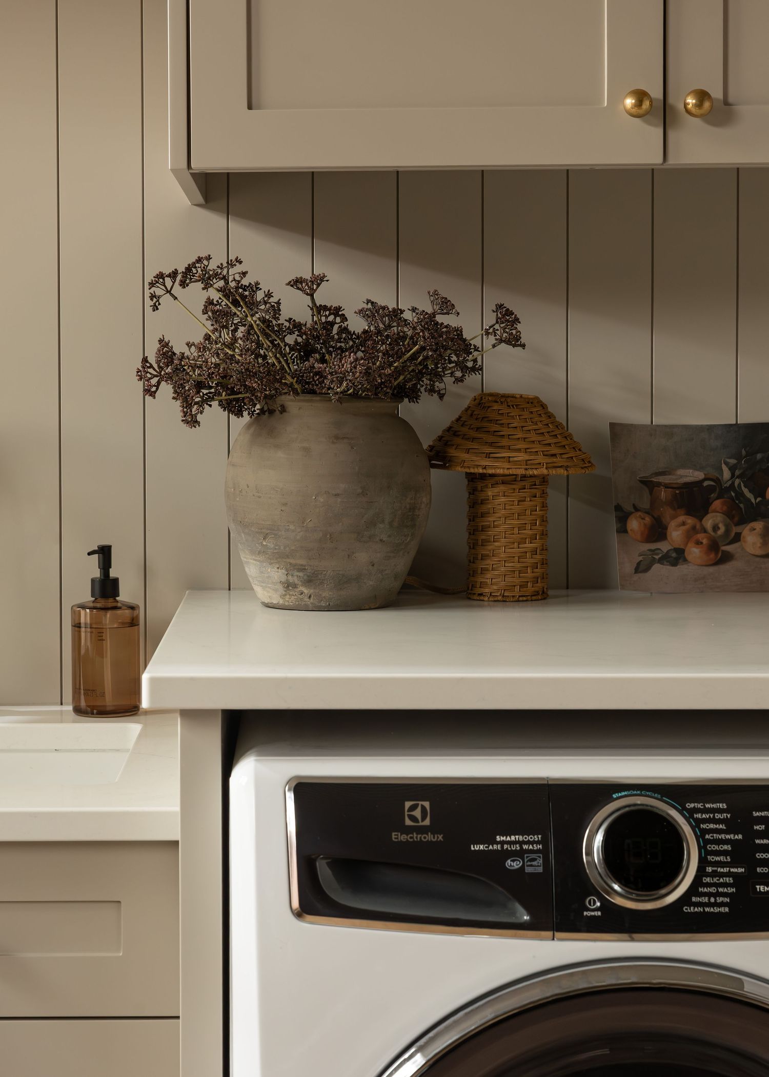Organized laundry room shelving with decorative baskets and dried flowers.