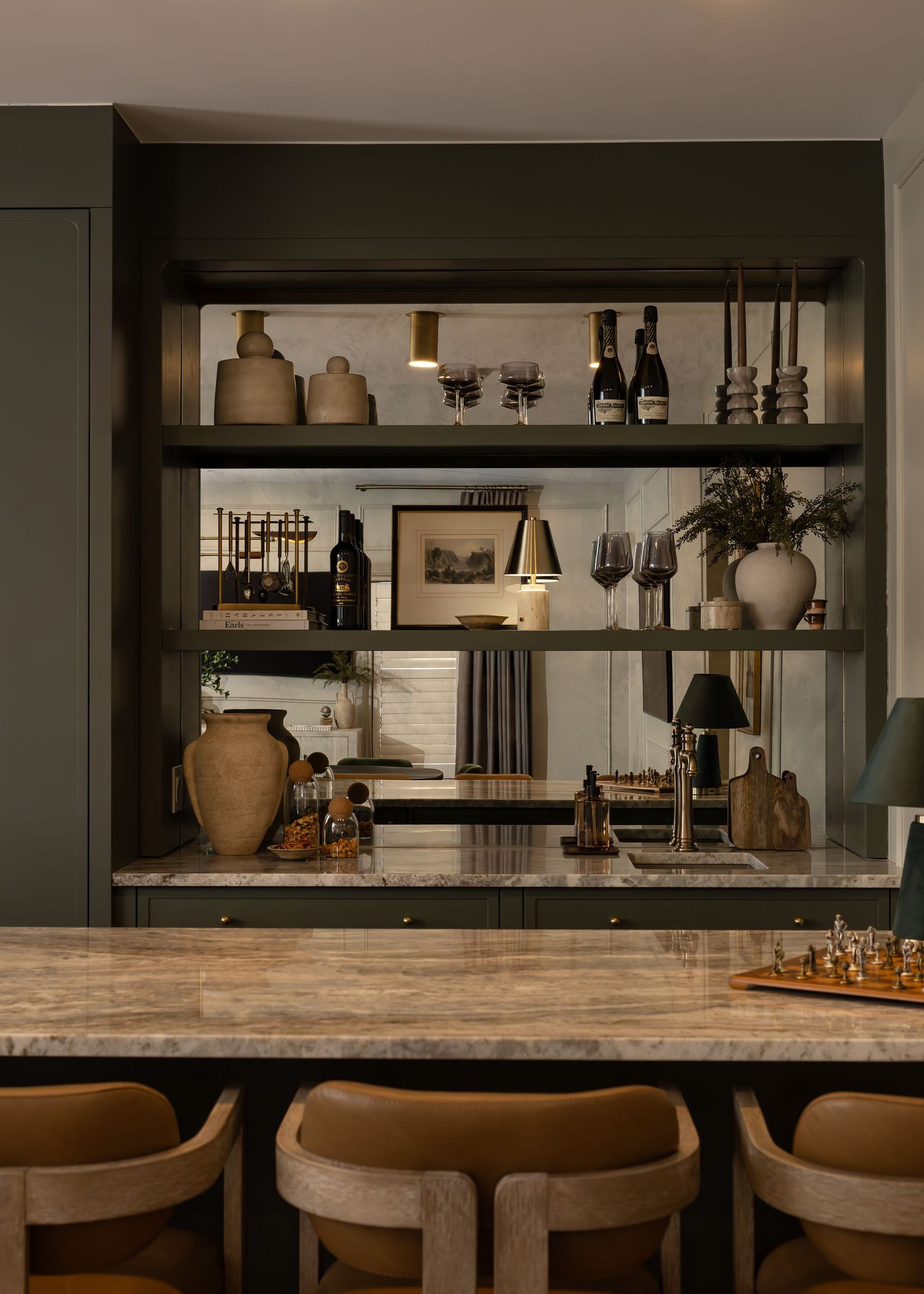 Upscale bar design featuring marble counters, leather seating, and built-in shelving for bottles.